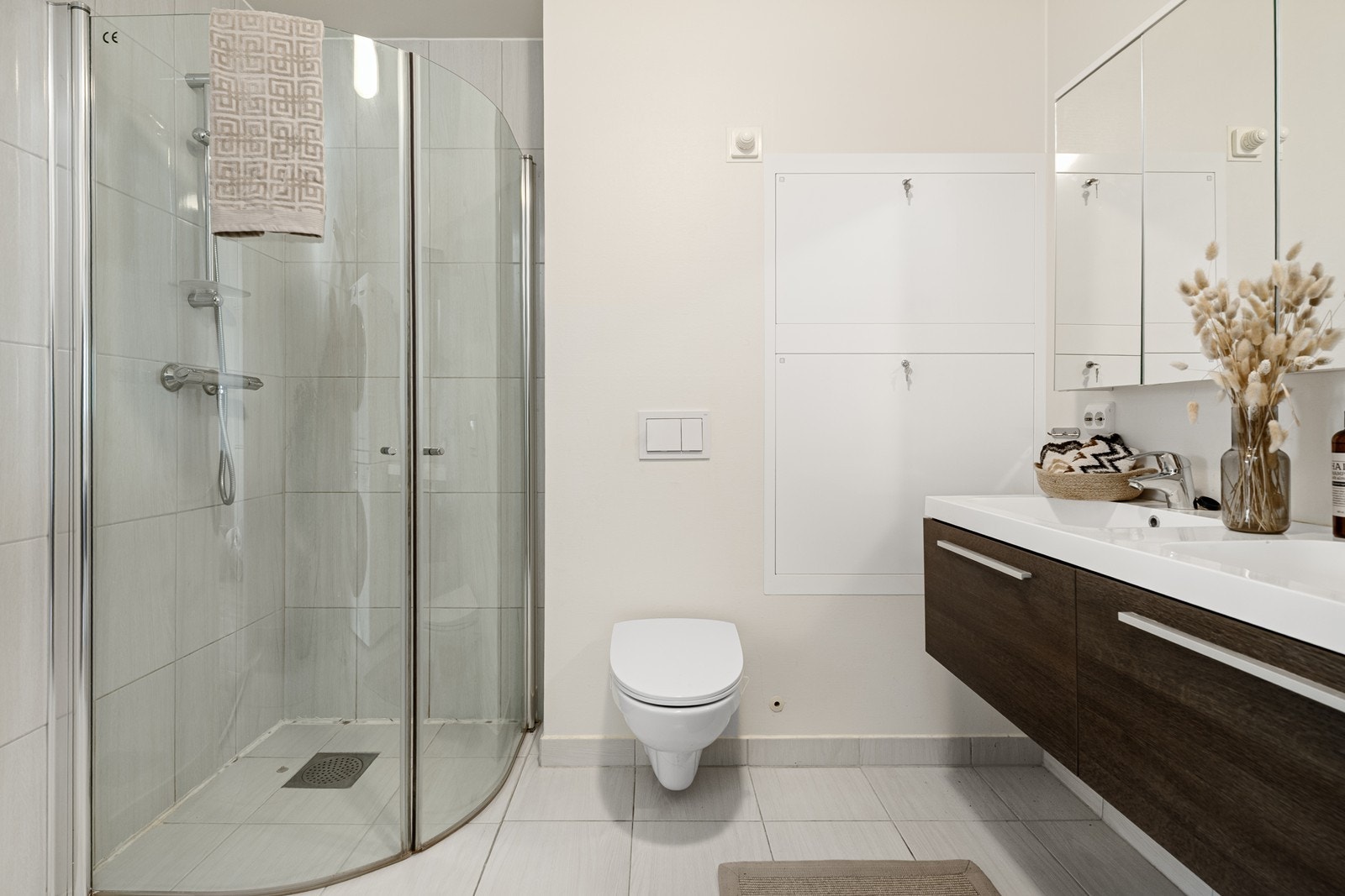 Badet har innredning med nedfelt dobbelvask, veggmontert toalett og dusjhjørne med dusjvegger. Det er også opplegg for vaskemaskin. Galleribilde