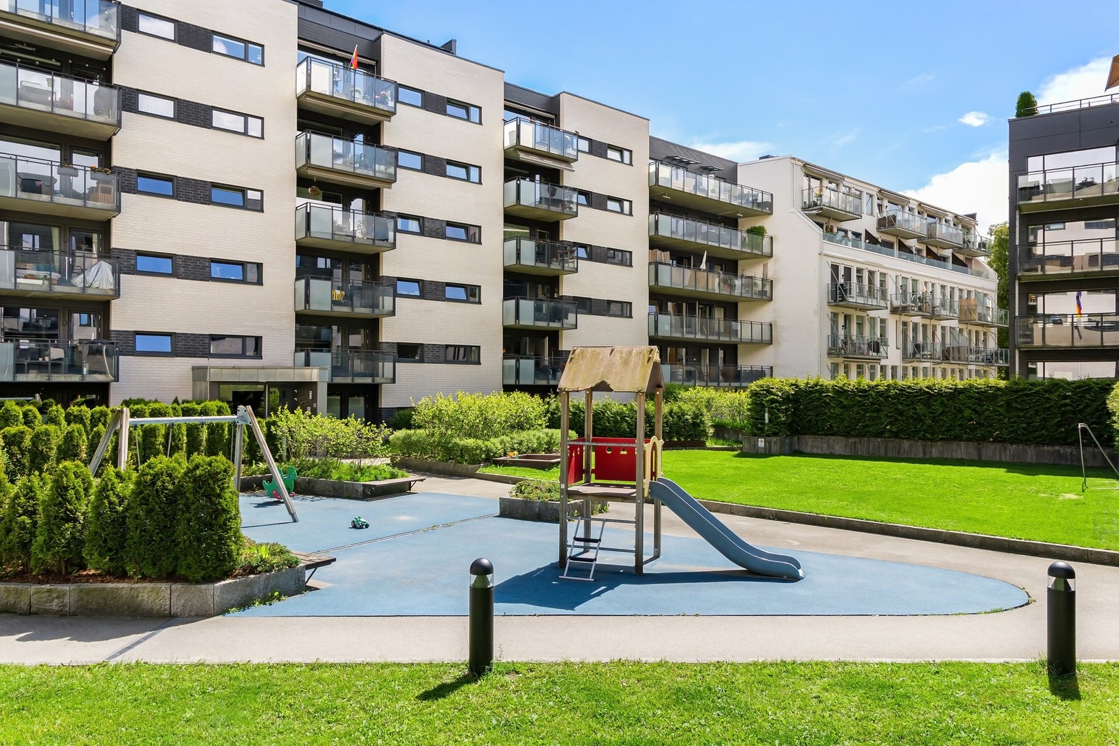 Barnevennlig bakgård med klatrestativ, huskestativ, sandkasse og gressplen. Galleribilde