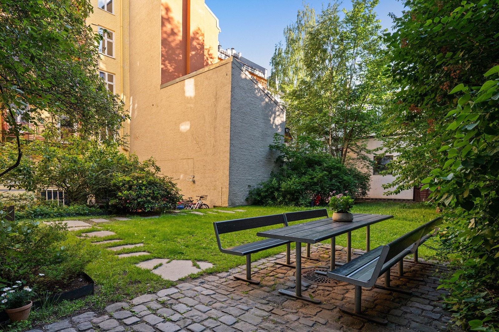 Bakgården er pent opparbeidet med gressplen, beplantning og steinlagte stier. Galleribilde