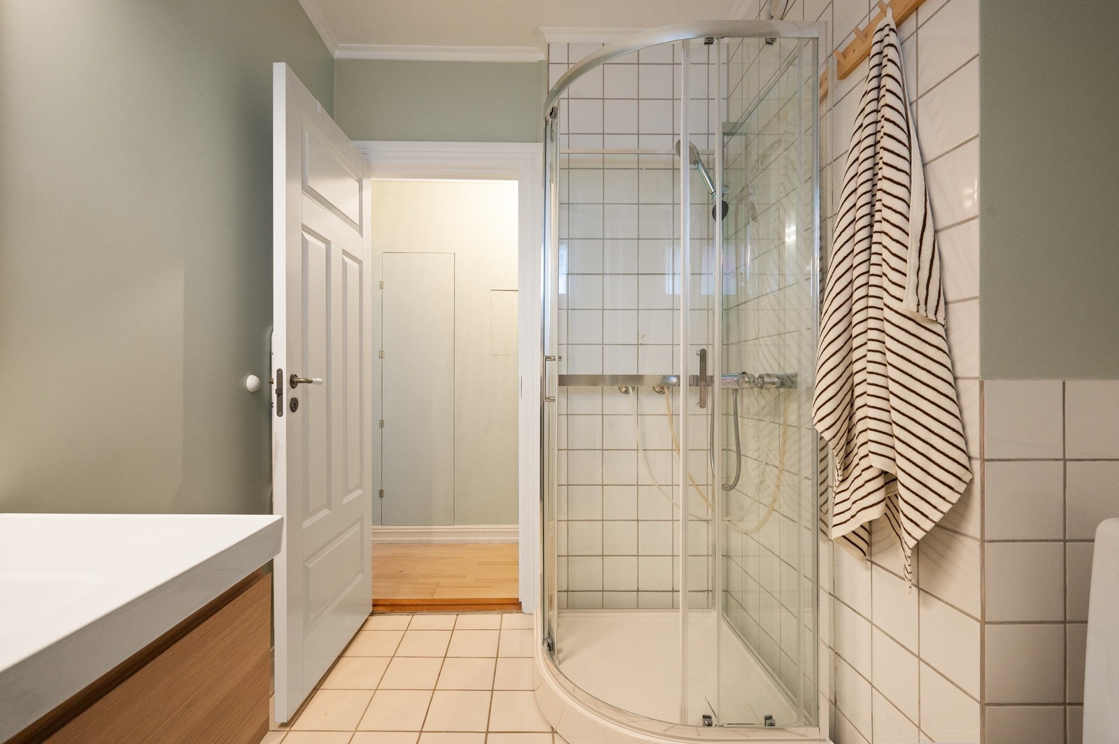 Badet er utstyrt med dusjkabinett og servant nedfelt i en moderne baderomsinnredning. Galleribilde