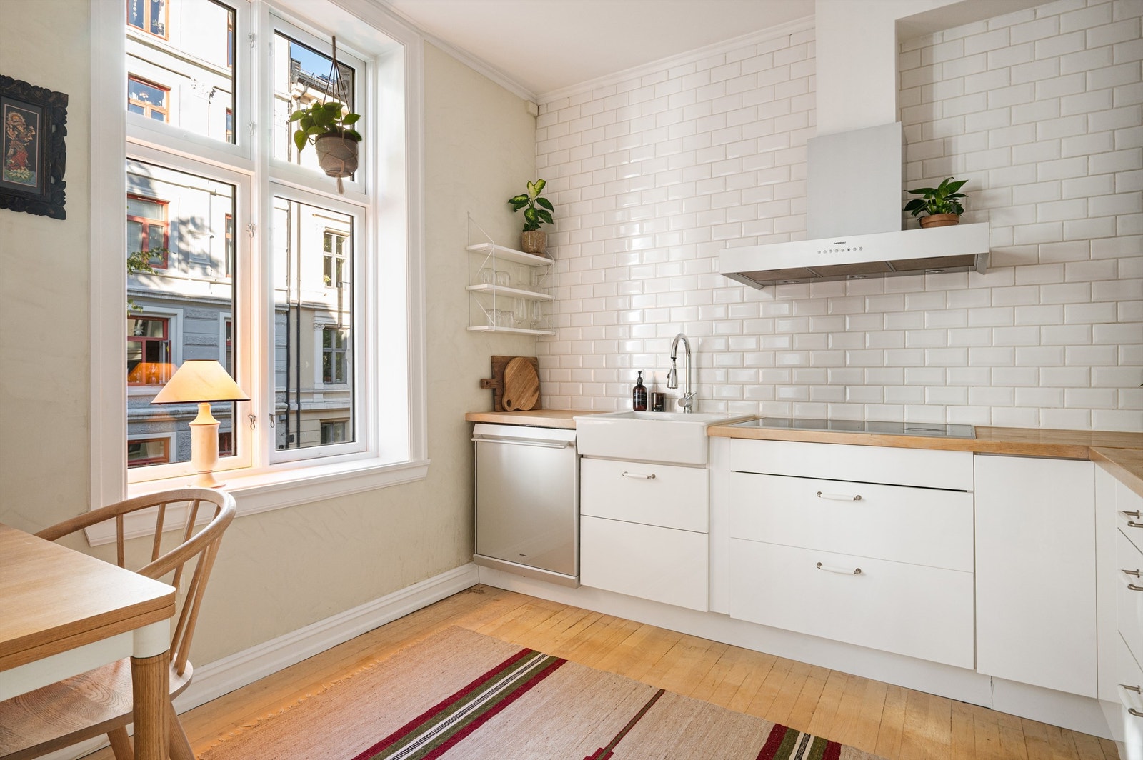 Lyse fliser på vegg over benkeplaten. Hvitevarene er integrerte med platetopp, stekeovn og kjøl/fryseskap fra leverandøren Gaggenau. Galleribilde