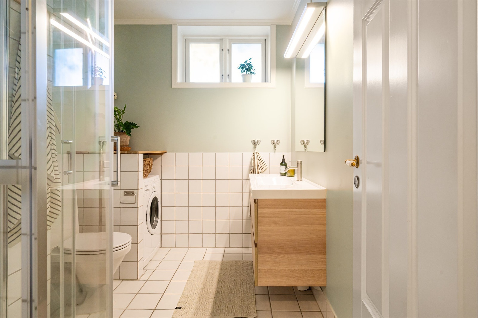 Romslig bad med flislagt gulv med elektrisk gulvvarme og opplegg for vaskemaskin. Galleribilde
