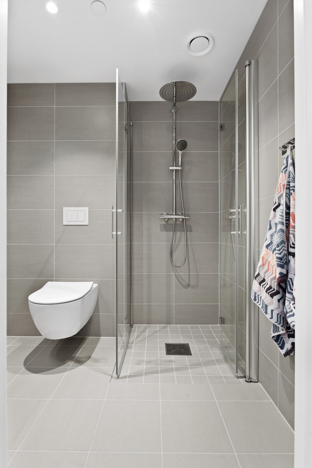 Badet er innredet med underskap, servant, speil med belysning over, stikk, vegghengt toalett og dusjhjørne med innfellbare dører. Galleribilde