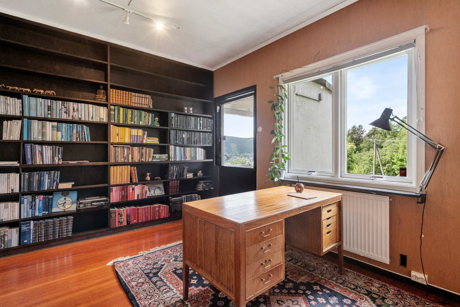 Stort bibliotek eller tv-stue med plassbygd bokhylle og utgang direkte til den flotte terrassen som har sol hele dagen. Galleribilde