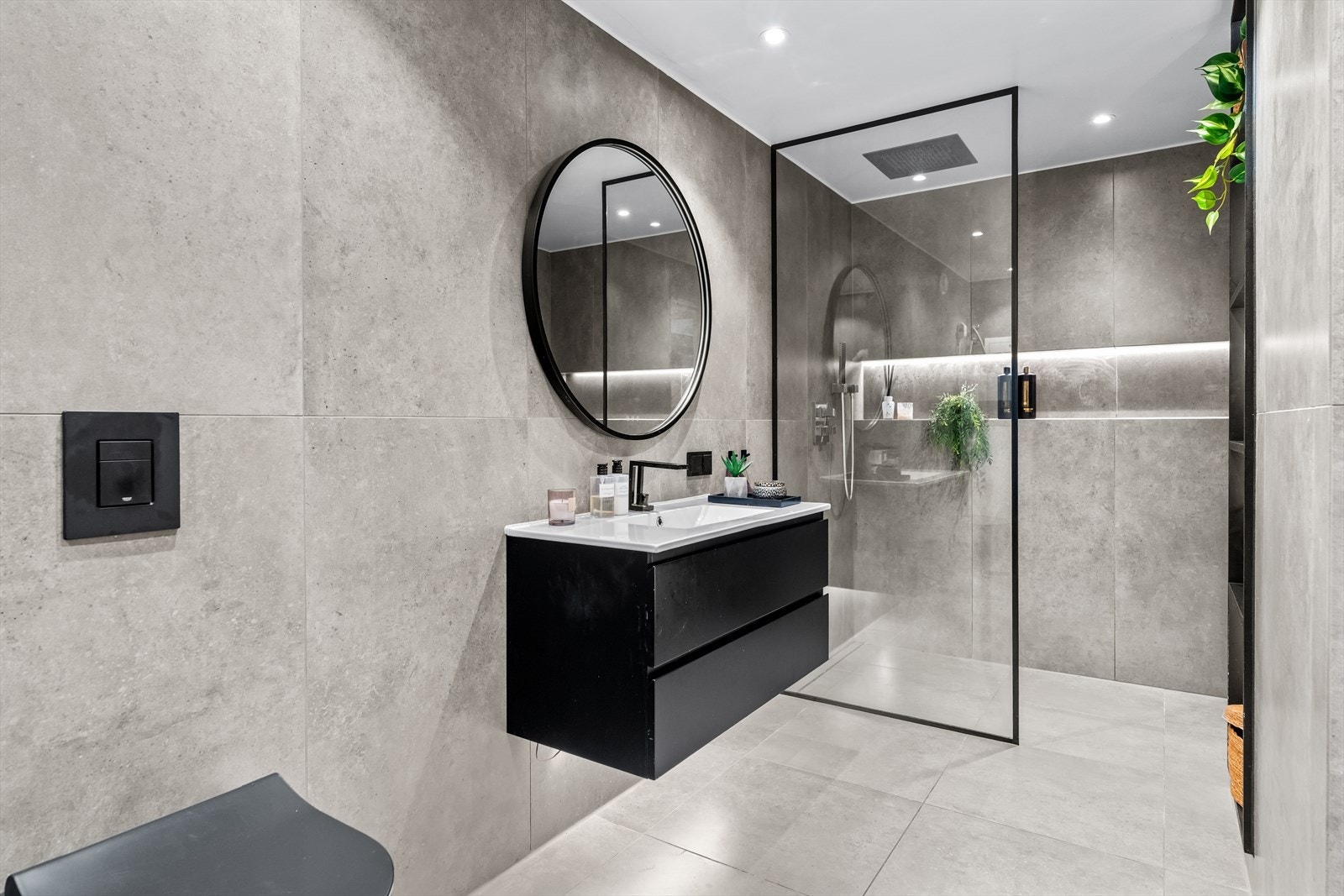 Delikat baderom med store fliser, moderne innredning og dusjsone med glassvegger. Det stilrene uttrykket gir badet en eksklusiv følelse. Galleribilde