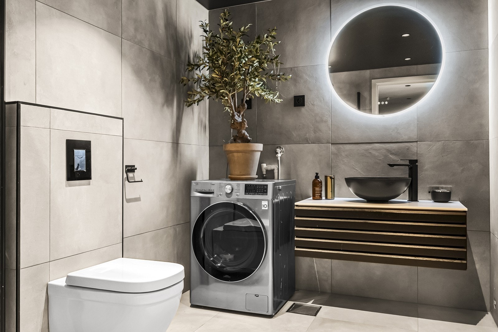 Badet i u. etg. fremstår tidsriktig og samtidig moderne, med store fliser, sort tak med downlights og stort speil med integrert lys. Galleribilde