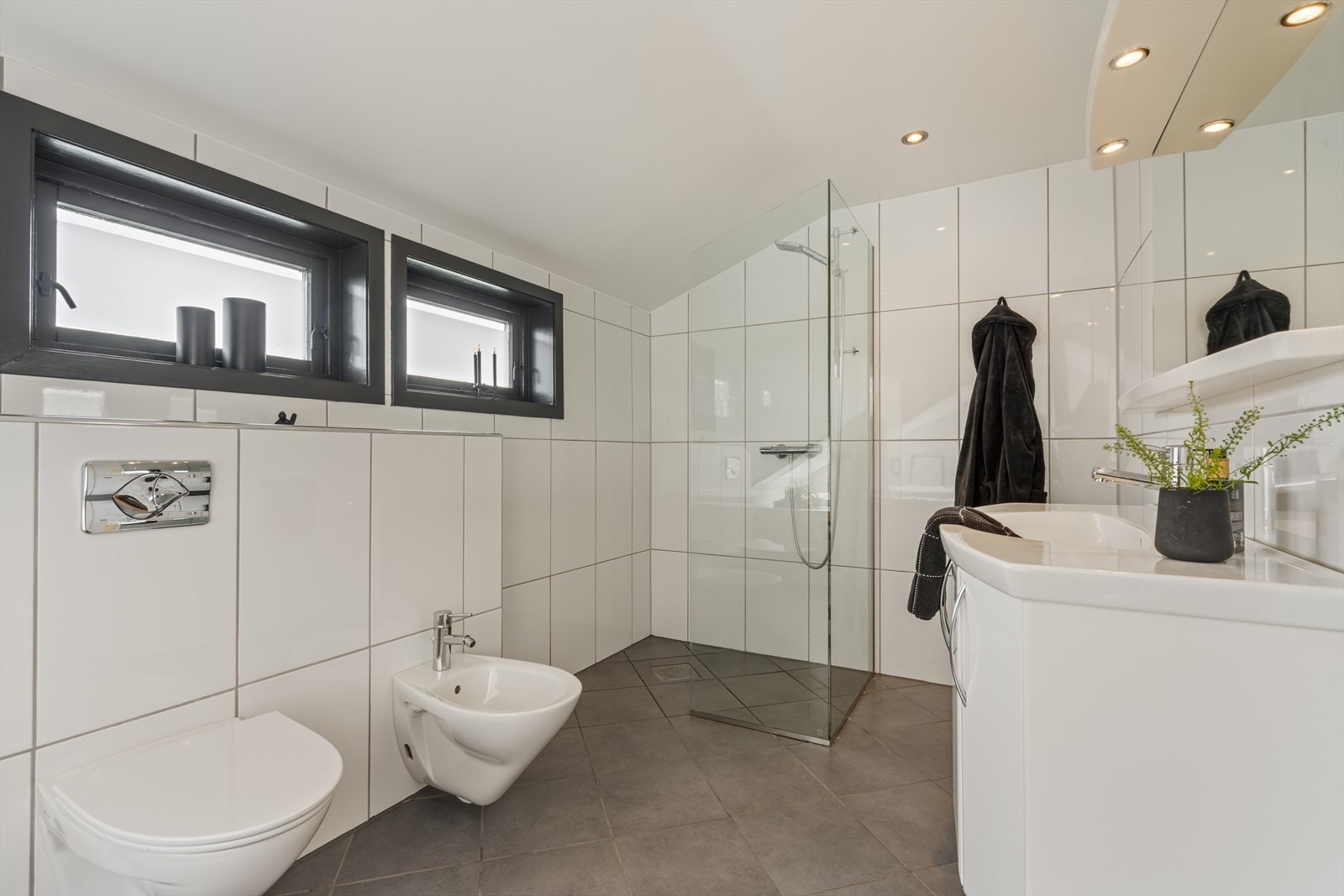 Det romslige badet tilknyttet foreldresoverommet har fliser på vegger og gulv, samt malte plater i tak. Rommet inneholder boblebadekar, dusjnisje, seksjon med blandebatteri, vegghengt toalett og bidé. Galleribilde