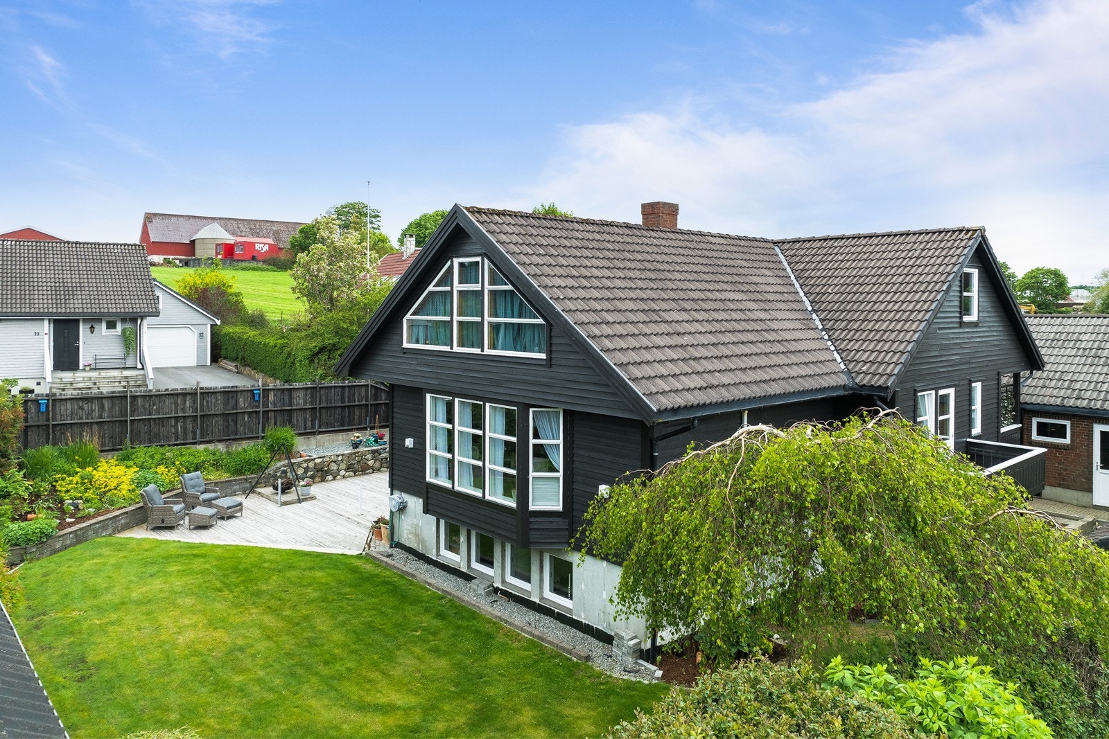 Pent opparbeidet uteområde med terrasse, plen og beplantning. Galleribilde