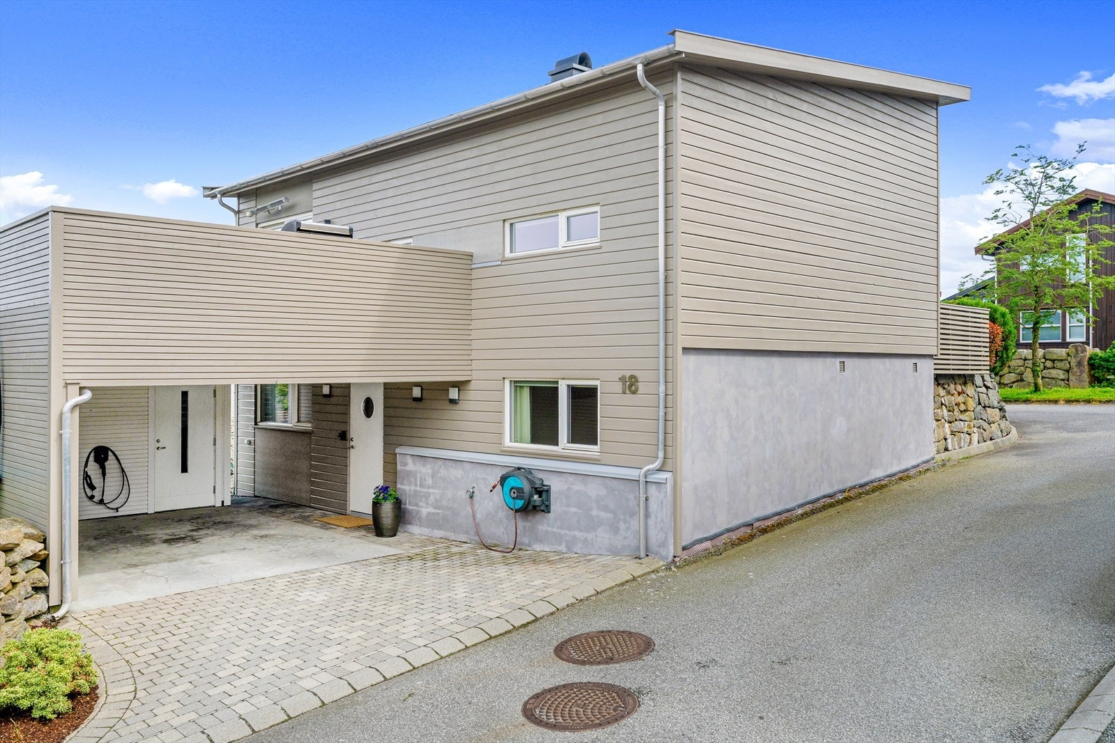 Parkering i carport med elbil-lader og to utvendige boder for praktisk oppbevaring. Galleribilde