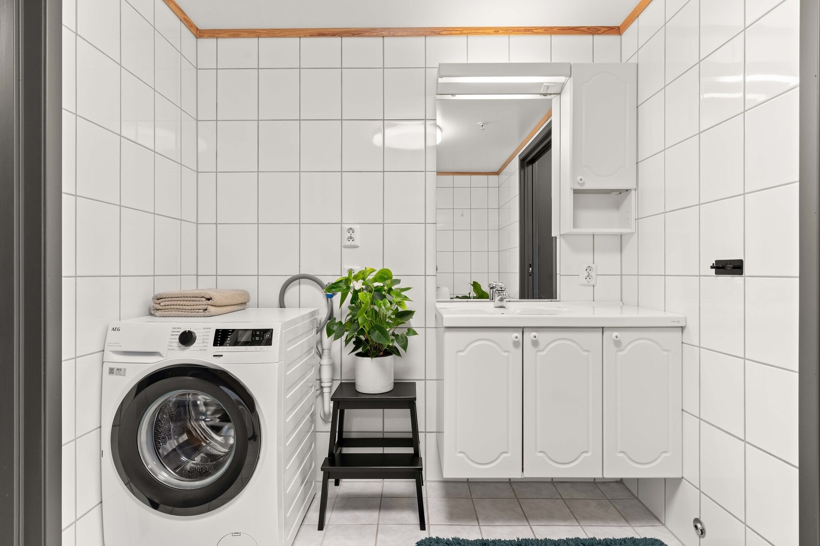 Badet er lyst og funksjonelt innredet med servantseksjon, dusjsone og opplegg for vaskemaskin Galleribilde