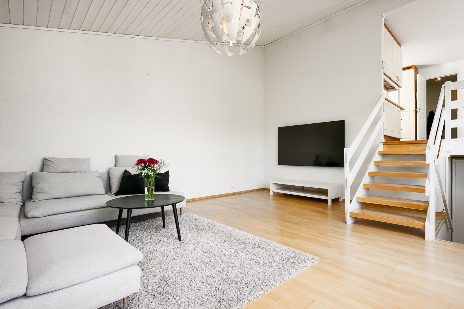 Boligen har en åpen stue- og kjøkkenløsning fordelt over halvplan, som skaper en luftig romfølelse og gir gode møbleringsmuligheter med naturlige soner for både hverdagsliv og sosiale sammenkomster Galleribilde