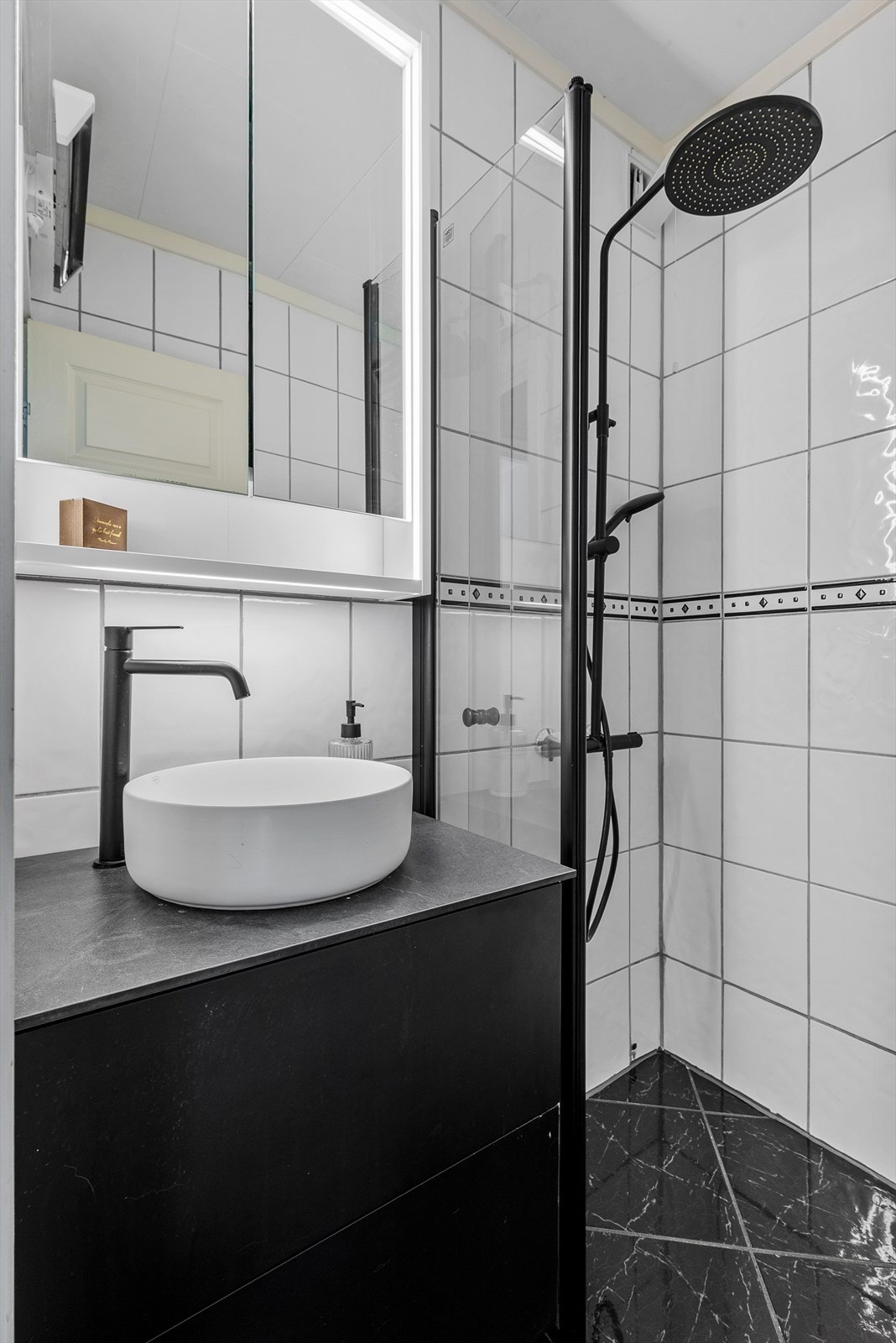 Badet er utstyrt med speil med speilskap, dushjørne og servant med servantskap. Galleribilde