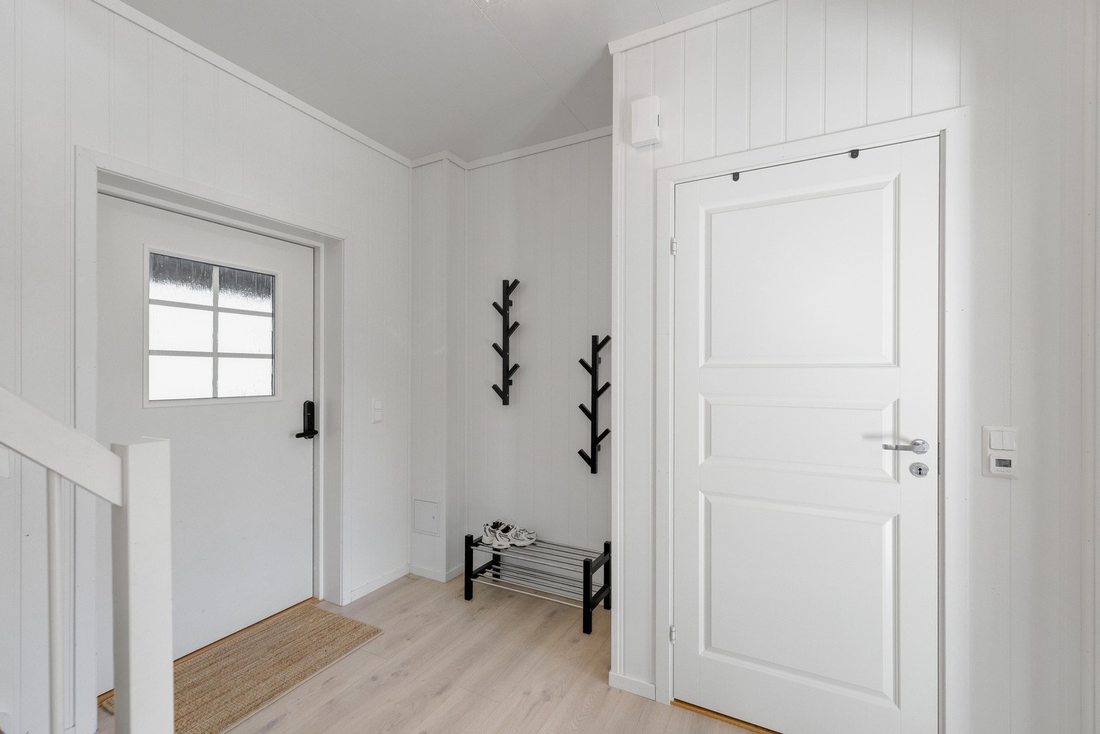 Boligen har adkomst via en romslig hall i 1. etasje, med trapp videre opp til boligens 2. etasje. Hallen gir et lyst og ryddig førsteinntrykk, med god plass til oppbevaring av yttertøy og sko. Herfra er det videre tilgang til bad, vaskerom og oppholdsrom, Galleribilde