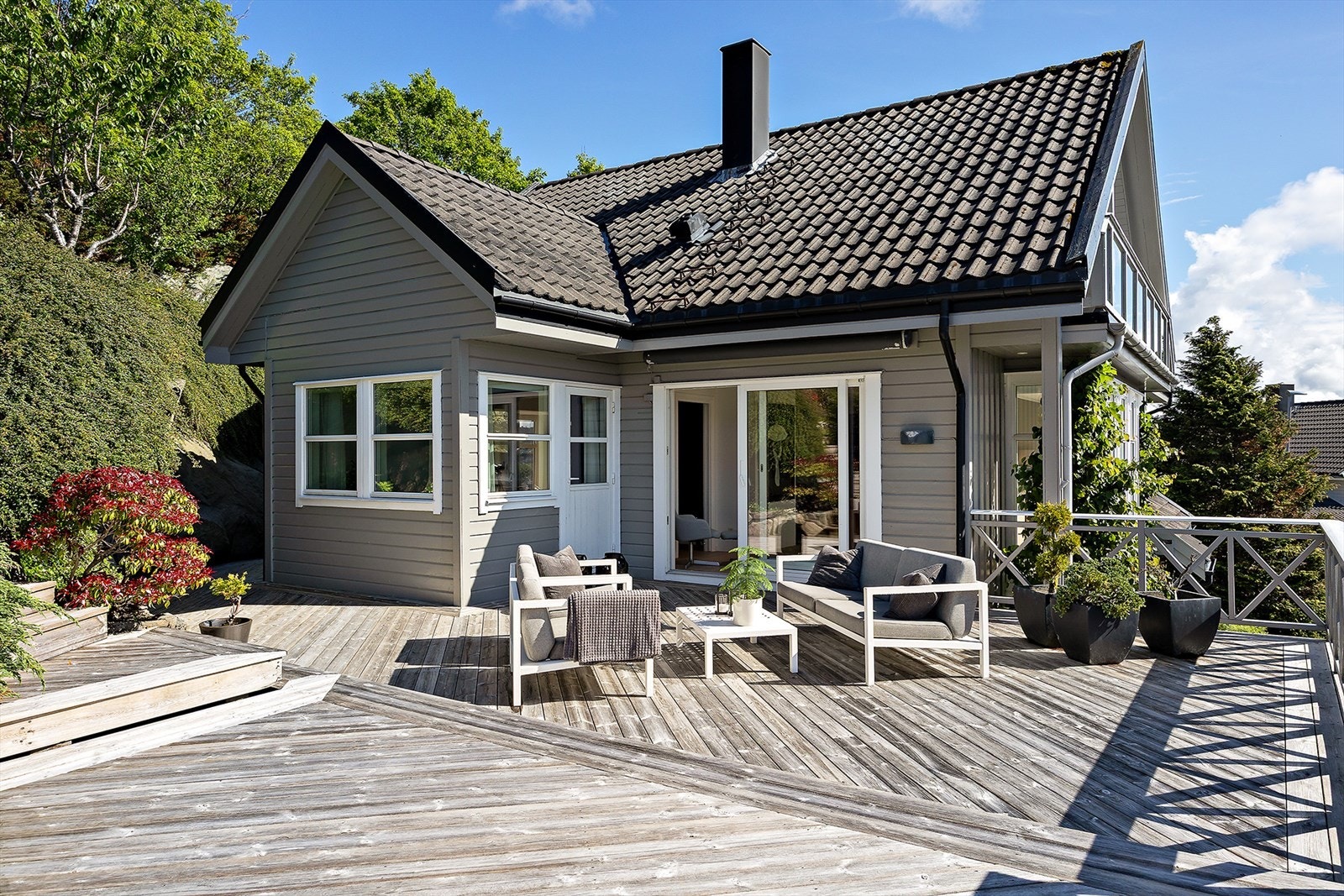 Tomten er pent opparbeidet med plen, beplantning og flere plattinger. Galleribilde