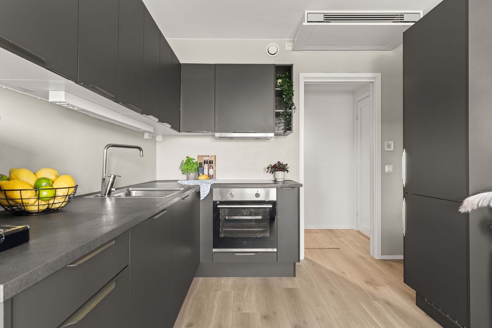 Kjøkkenet har mørke, elegante fronter og integrerte hvitevarer. Her kombineres stilrent design med praktiske arbeidsflater. Galleribilde