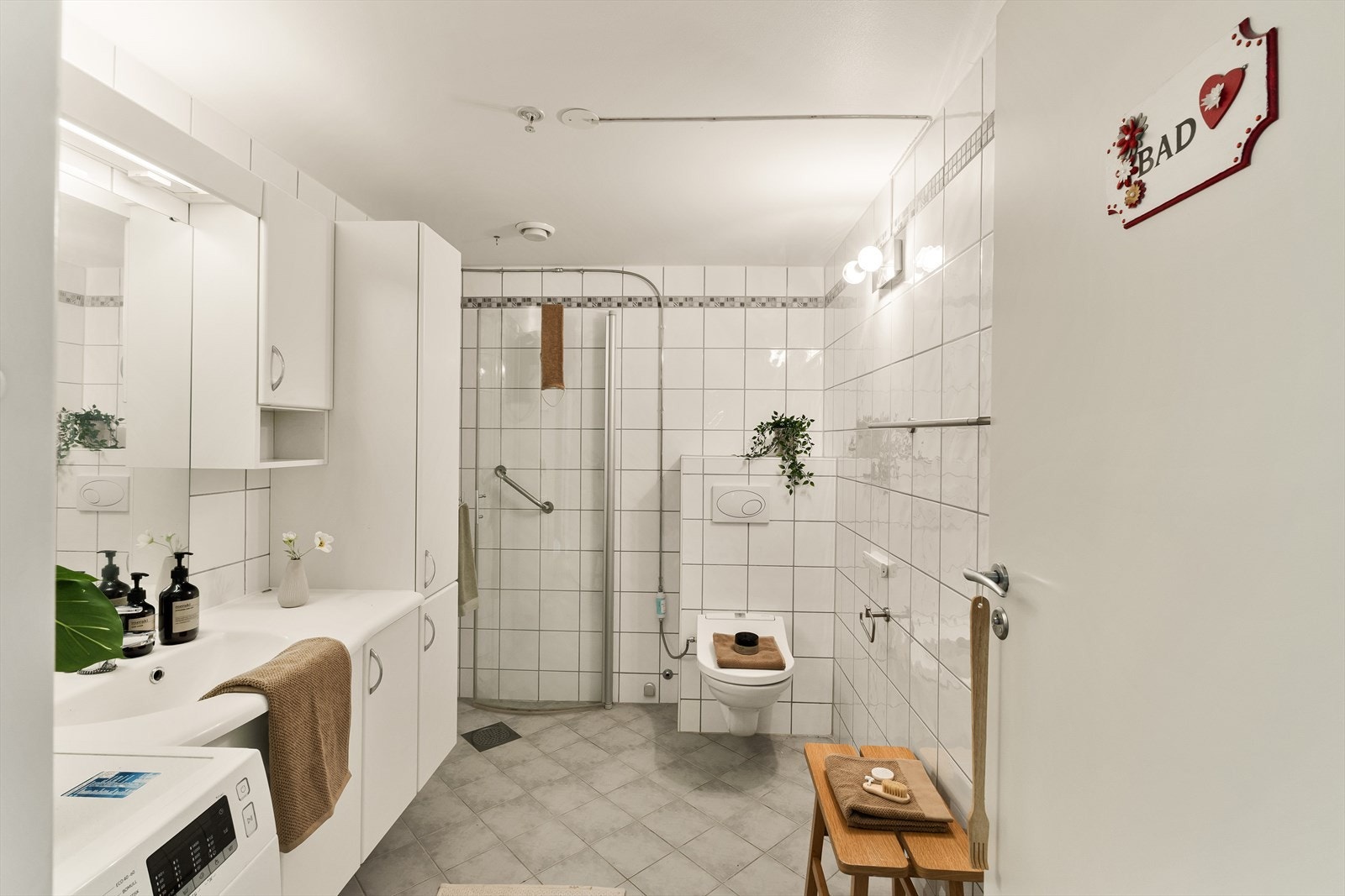 Det er varmekabler i gulv og rommet er innredet med nedfelt servant, vegghengt toalett og dusjhjørne/vegger. Galleribilde