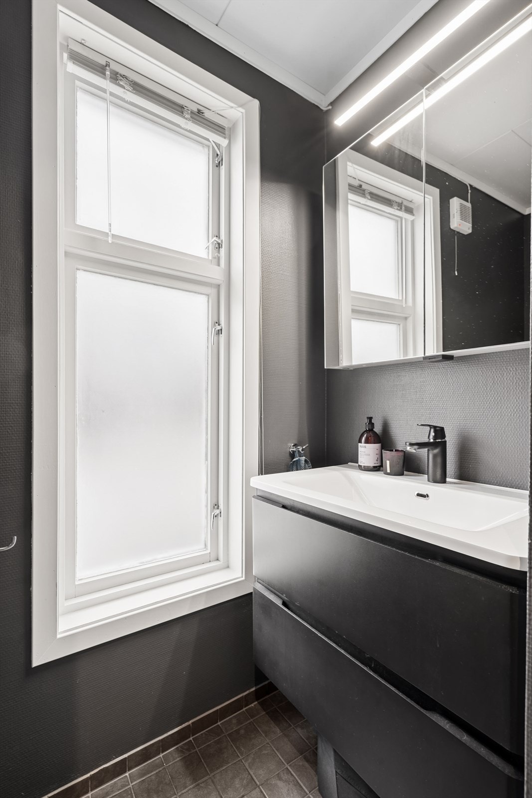 Badet er innredet med servant over innredning med skuffer, speilskap og belysning. Galleribilde