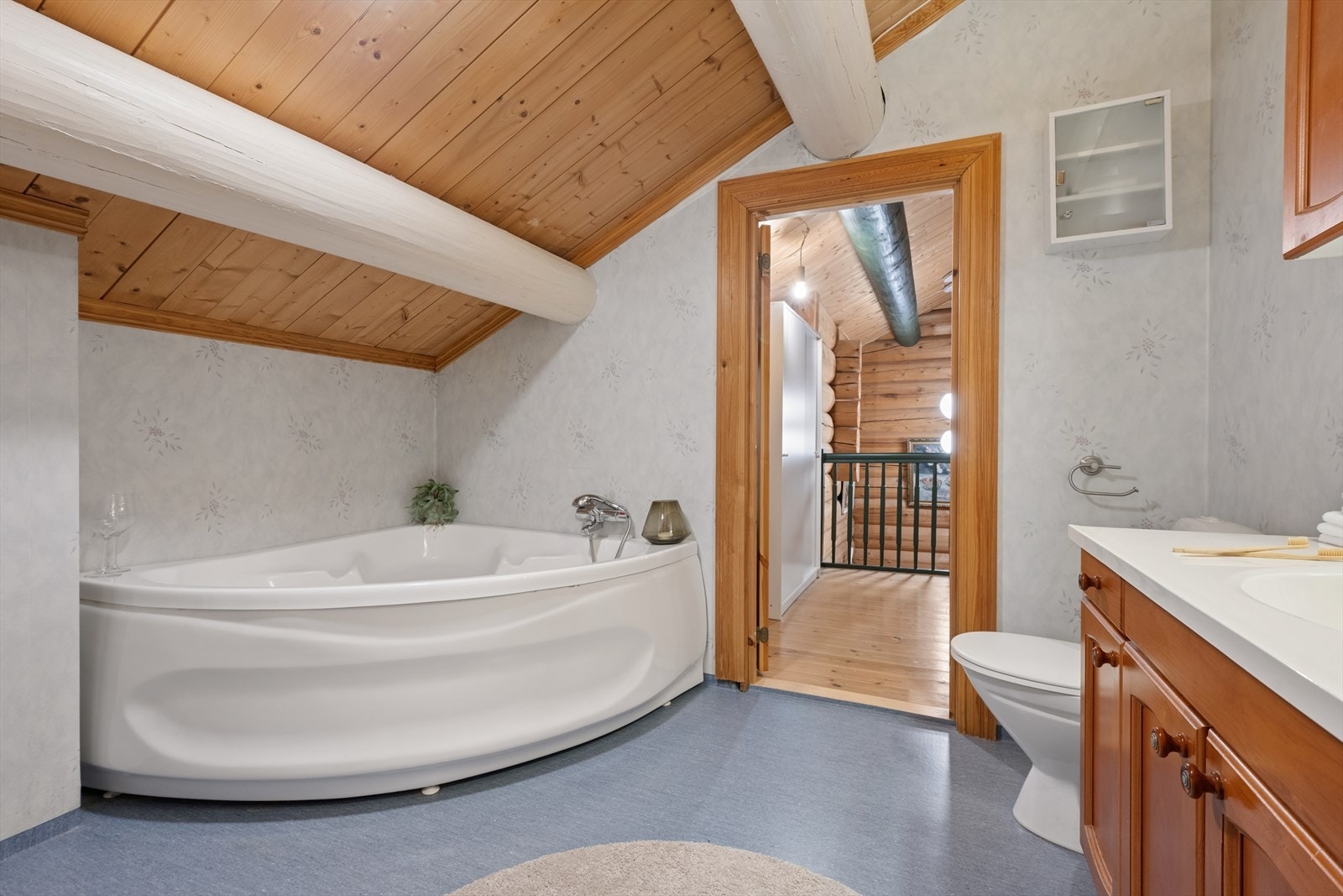 Her kan du slappe av i et romslig hjørnebadekar. Badet har vinylbelegg på gulv og våtromstapet på veggene. Galleribilde