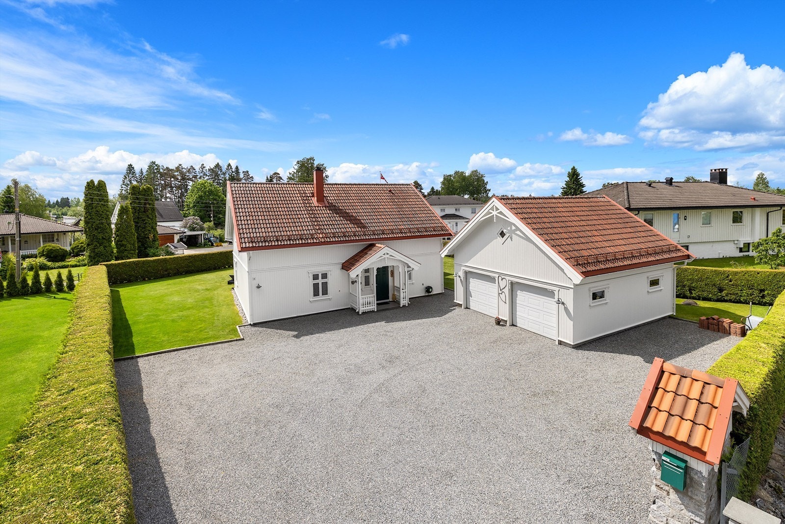 Stor, gruset gårdsplass med rikelig av biloppstillingsplasser foran huset og garasjen. Galleribilde