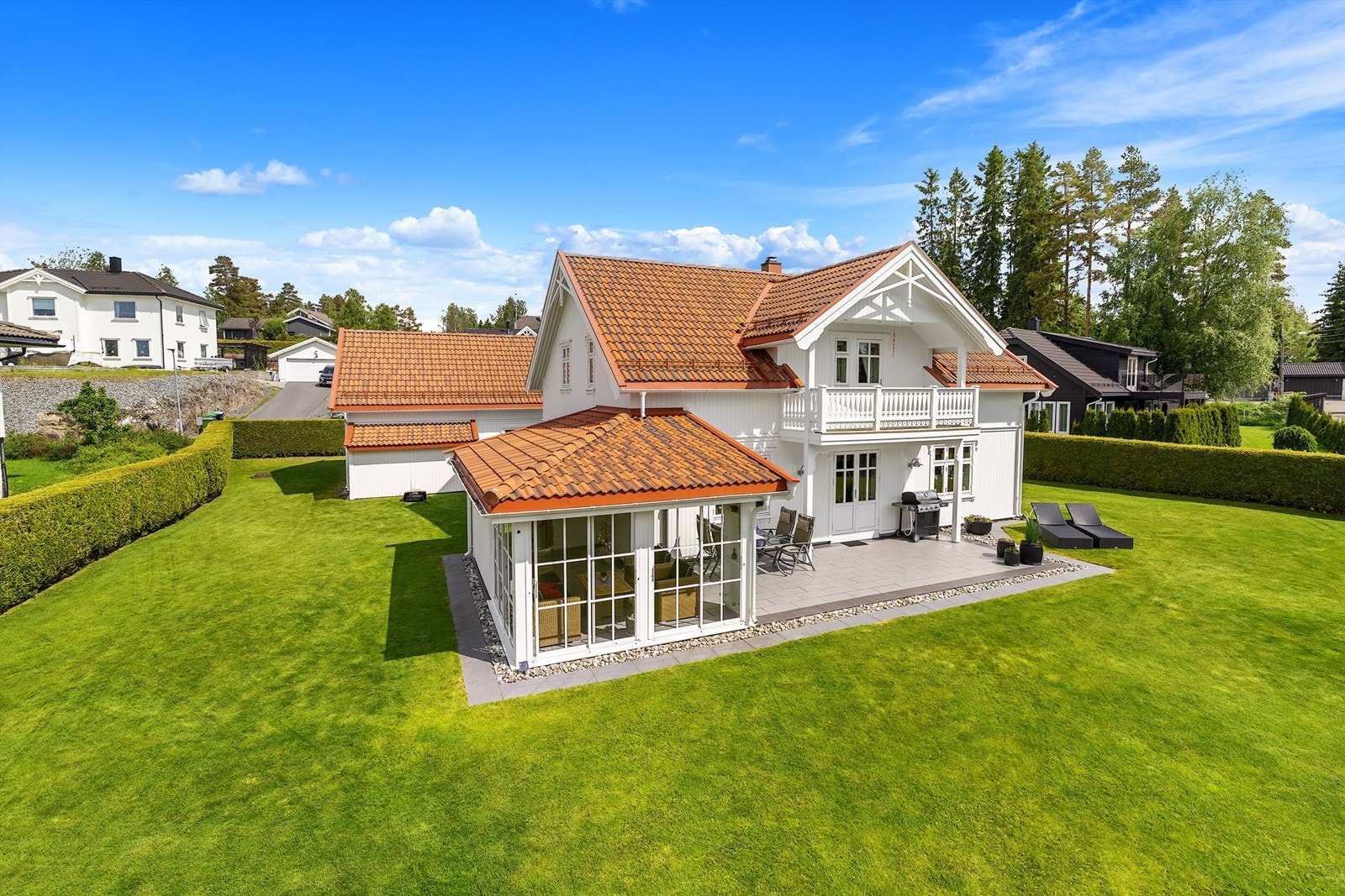 Tomten er pent opparbeidet med en stor, flat plen og hekk som rammer inn eiendommen. Galleribilde