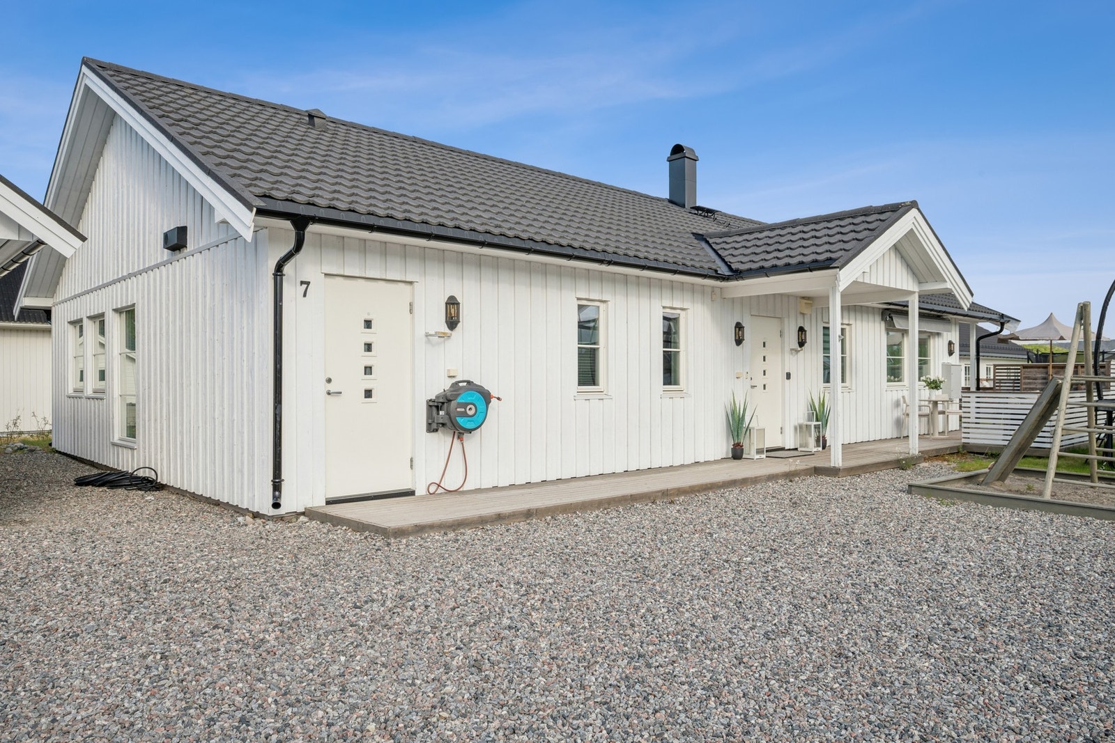 Gruset innkjørsel og parkeringsområde foran huset og garasjen. Galleribilde