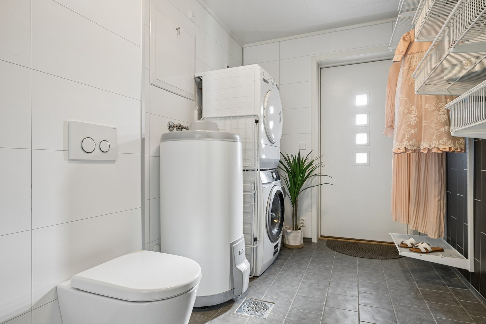 Praktisk vaskerom med egen inngang, vegghengt toalett og opplegg for vaskemaskin. Galleribilde