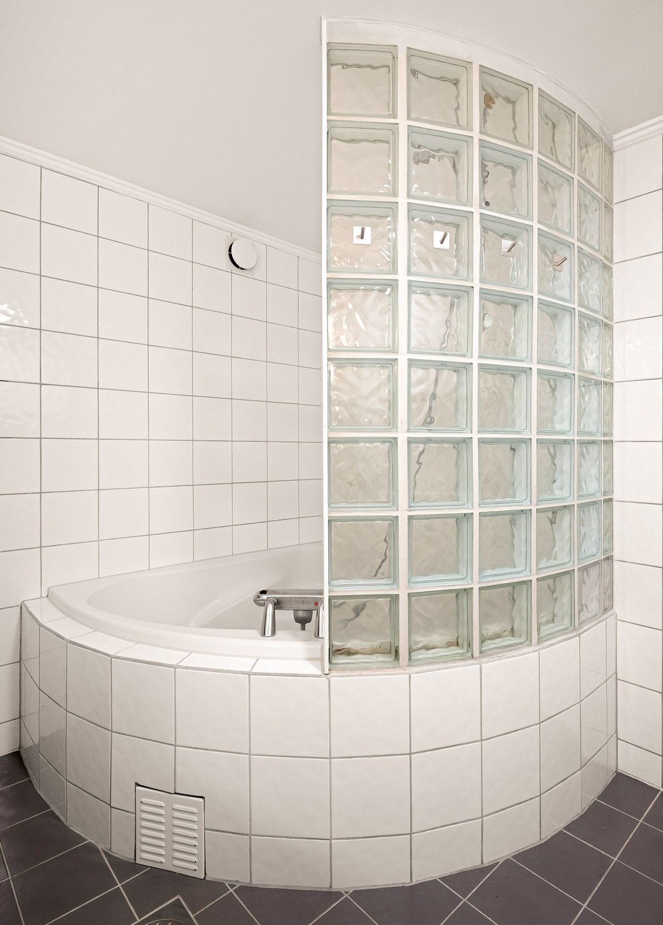 Videre inneholder badet vegghengt toalett og et innmurt badekar med murt vegg av glassbetong. Galleribilde