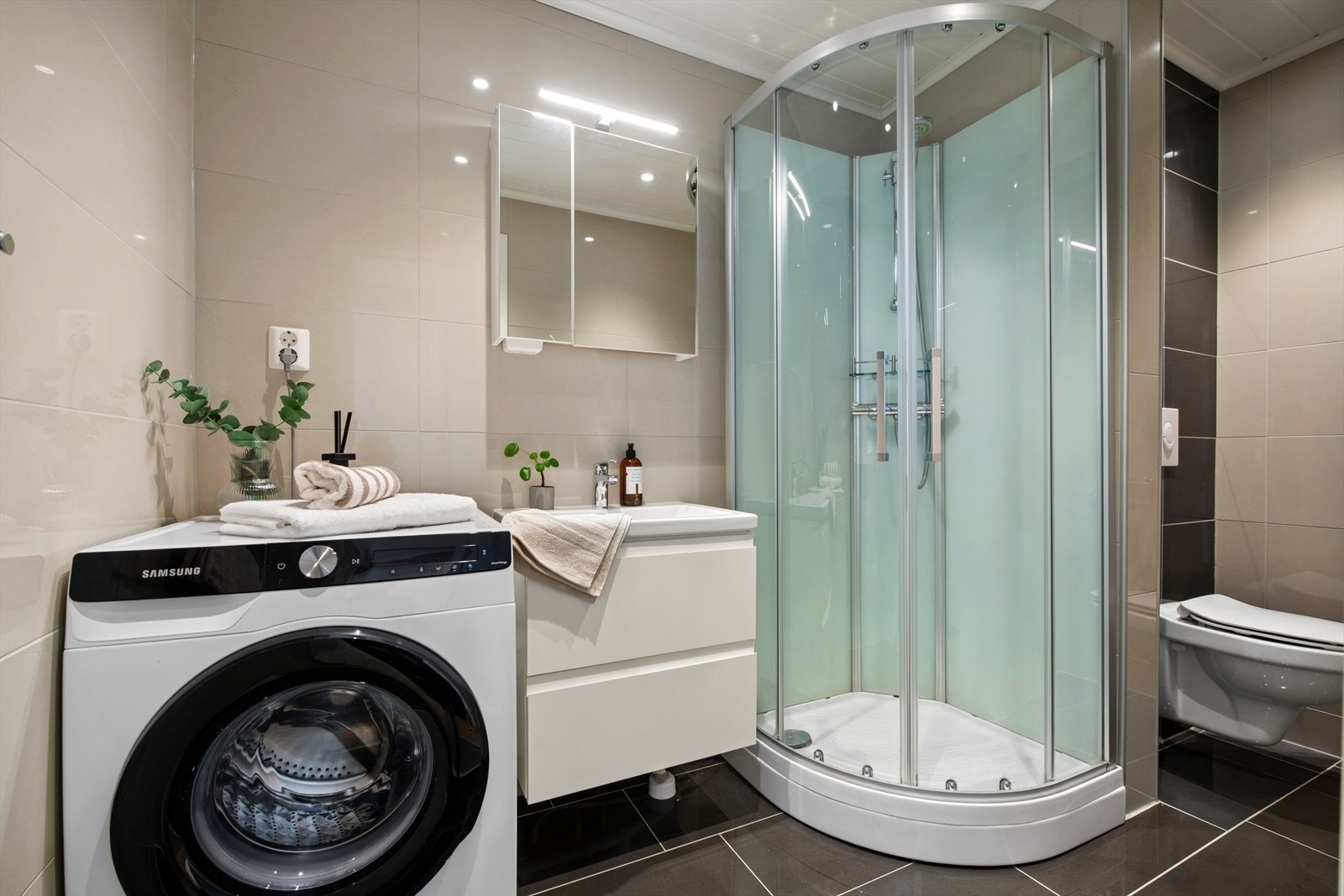 Badet er utstyrt med dusjkabinett, vegghengt toalett og elektrisk gulvvarme. Galleribilde