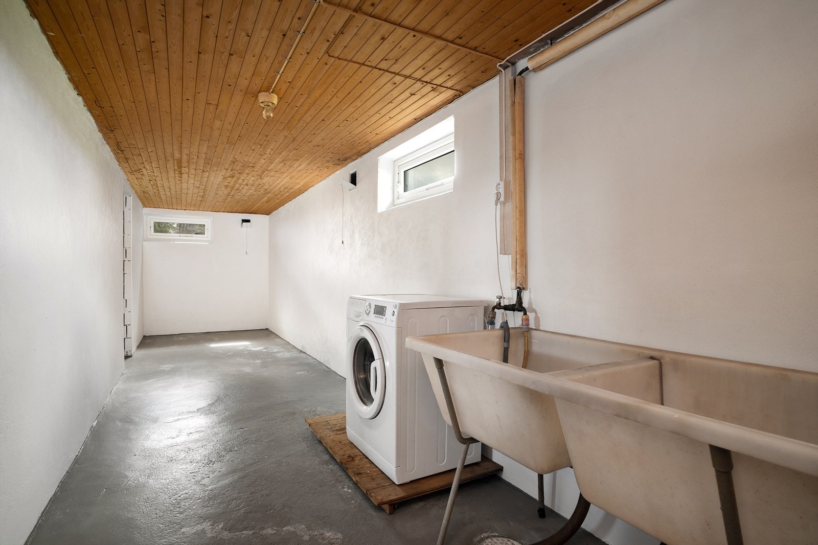 Praktisk vaskekjeller med malt betonggulv, skyllekum og opplegg for vaskemaskin. Galleribilde