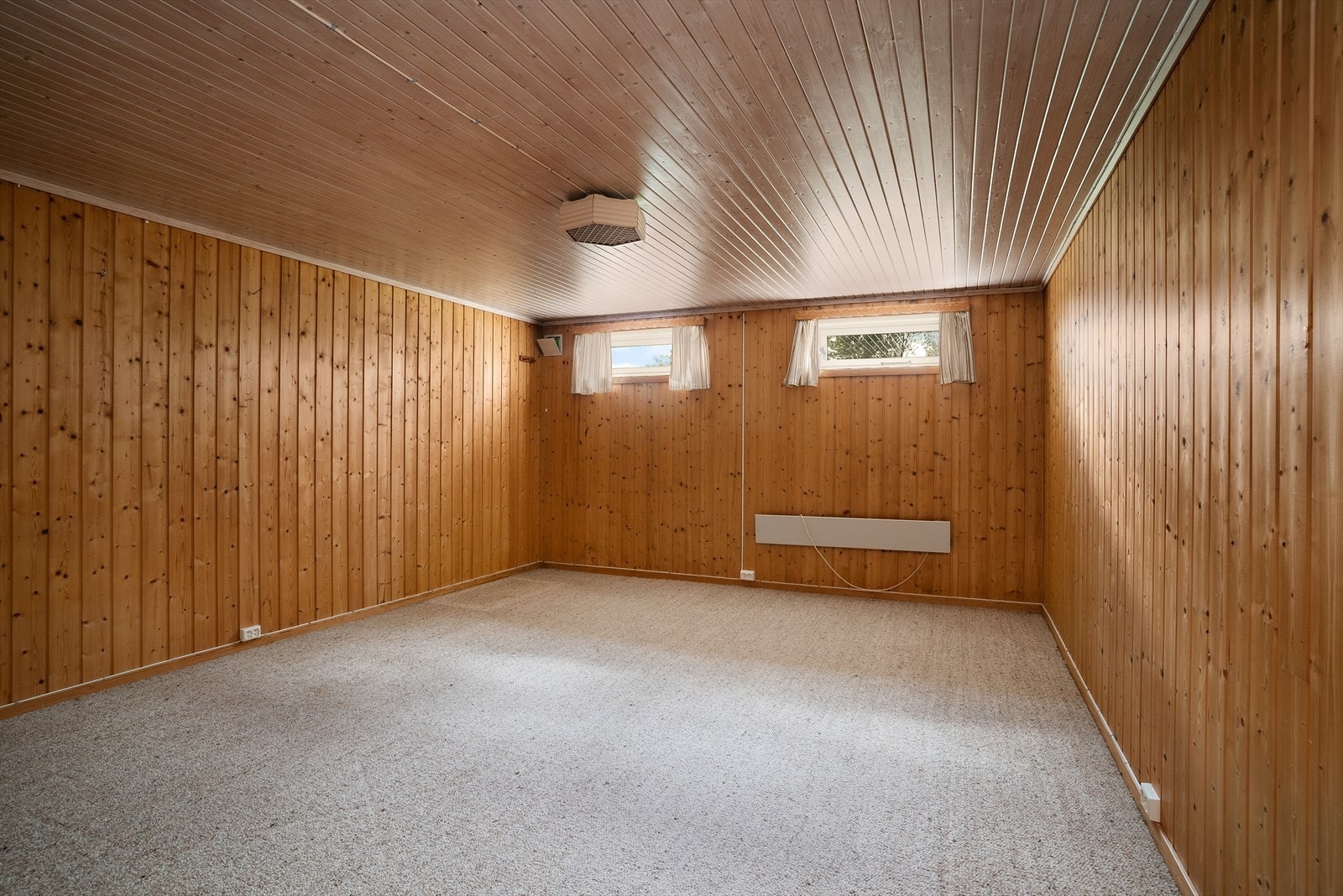 Innredet rom i kjelleren med teppe på gulv og panel på vegger. Rommet er ikke omsøkt eller godkjent for varig opphold. Galleribilde