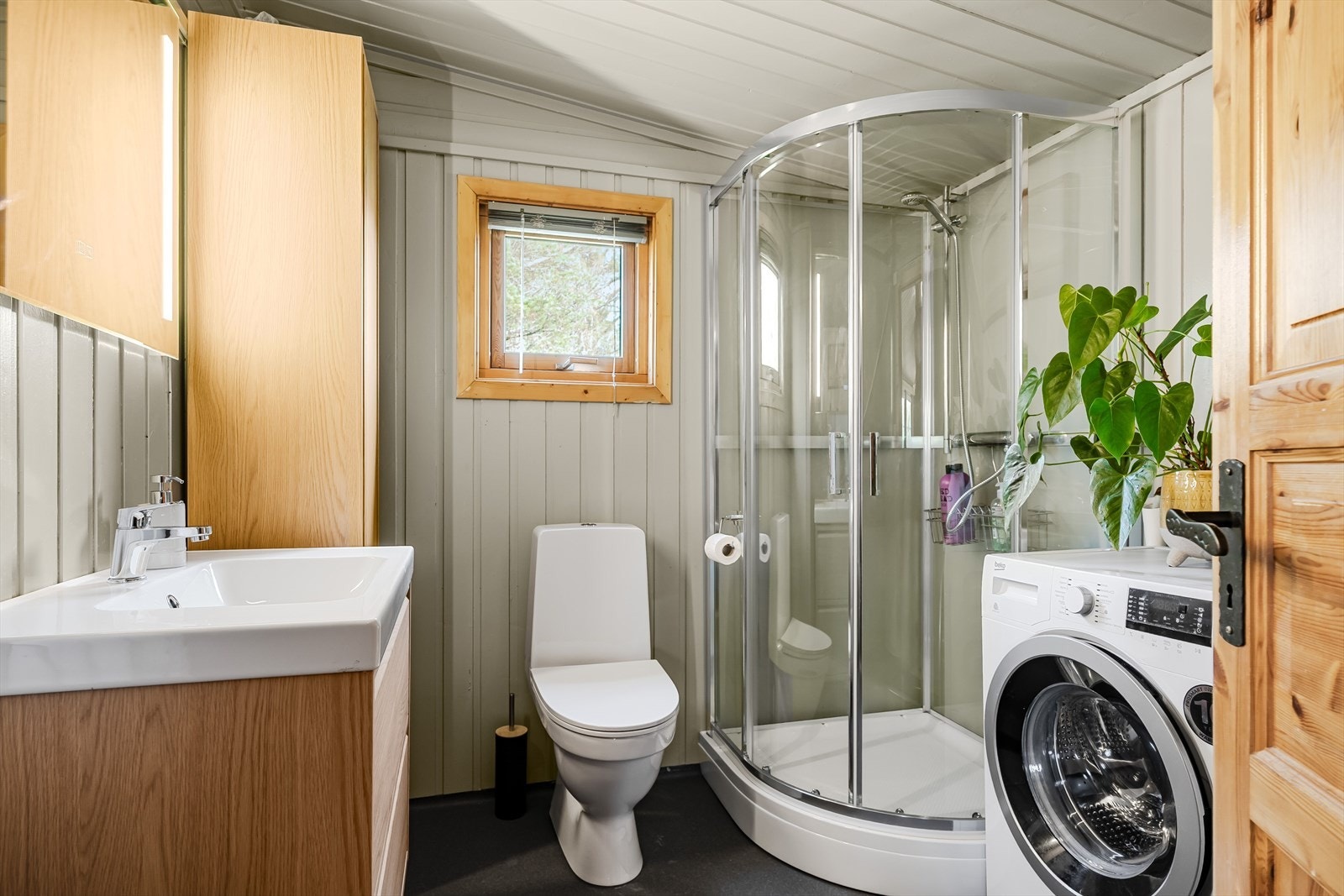 Badet har dusjkabinett, baderoms innredning, wc og opplegg for vaskemaskin. Galleribilde
