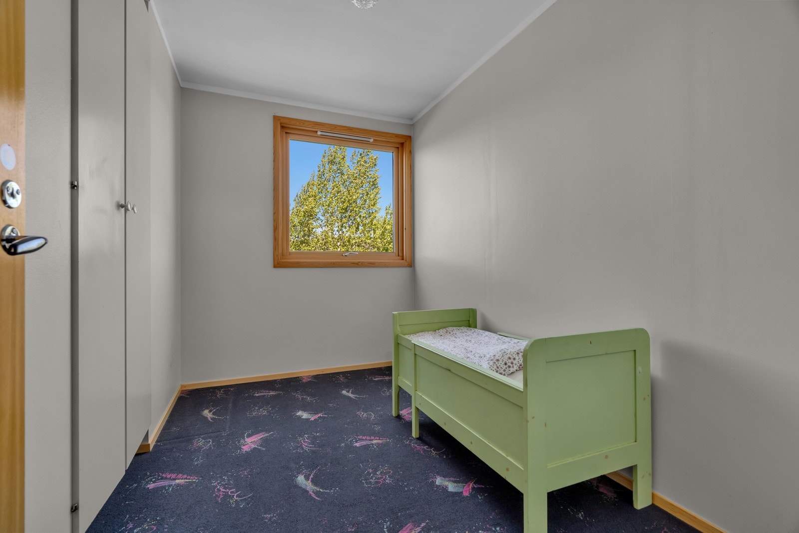 Soverom I med teppe på gulv, malt strie på veggene og skap i vegg. Galleribilde