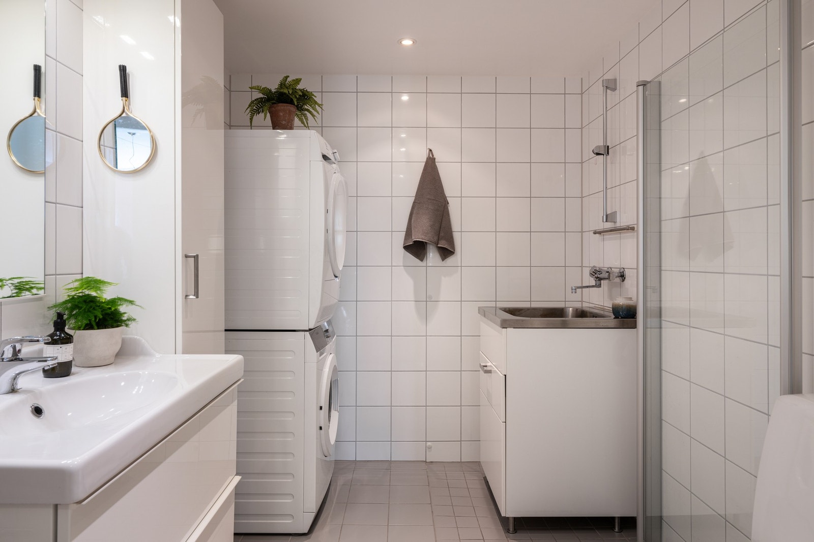Et praktisk kombinert WC/vaskerom med toalett, servantinnredning, utslagsvask med tilhørende benkeskap, samt opplegg for vaskemaskin og tørketrommel. Galleribilde