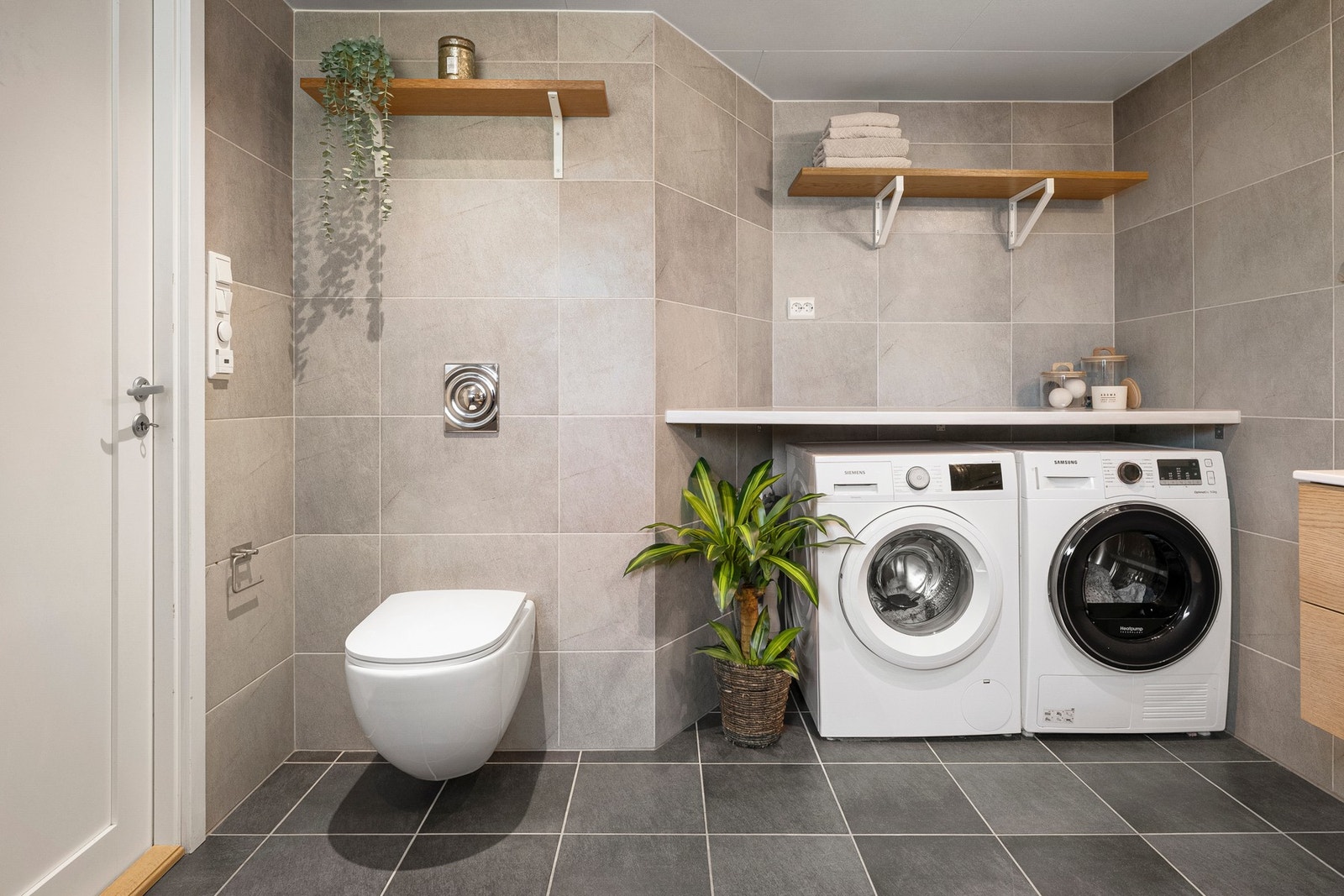 Badet er innredet med badekar med dusjløsning, vegghengt toalett, servantinnredning og opplegg for vaskemaskin og tørketrommel. Galleribilde