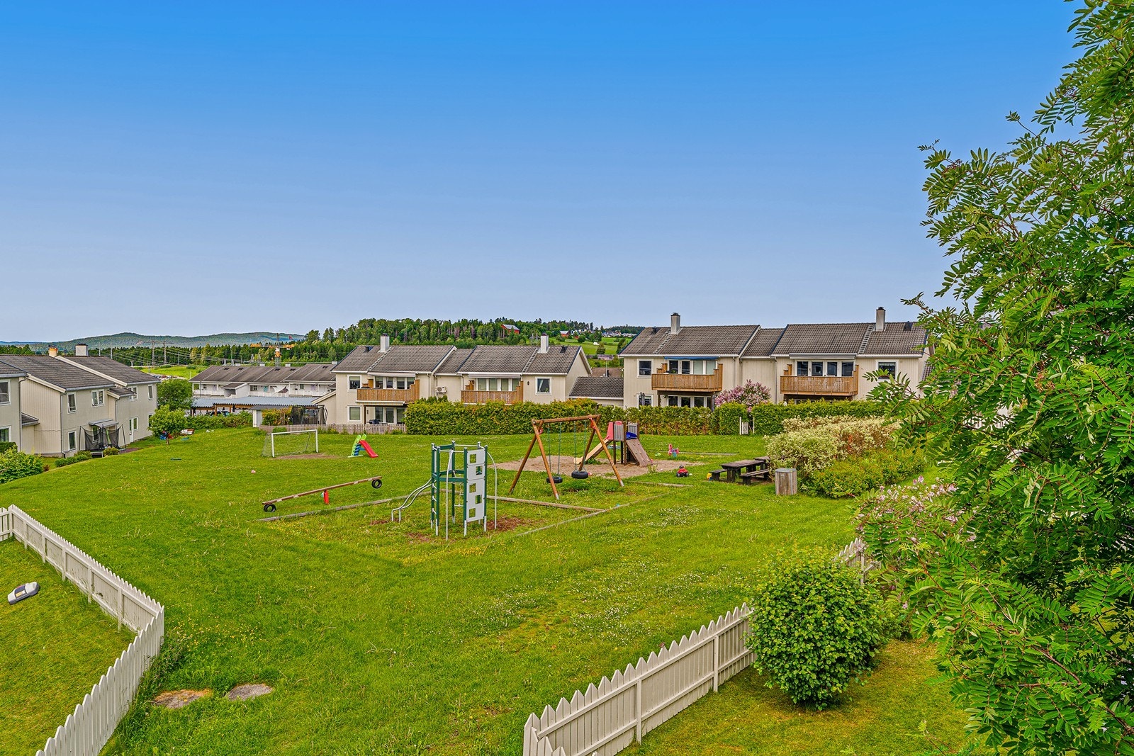 Store, pent opparbeidede fellesarealer med gressplen og lekeplass for beboerne. Galleribilde