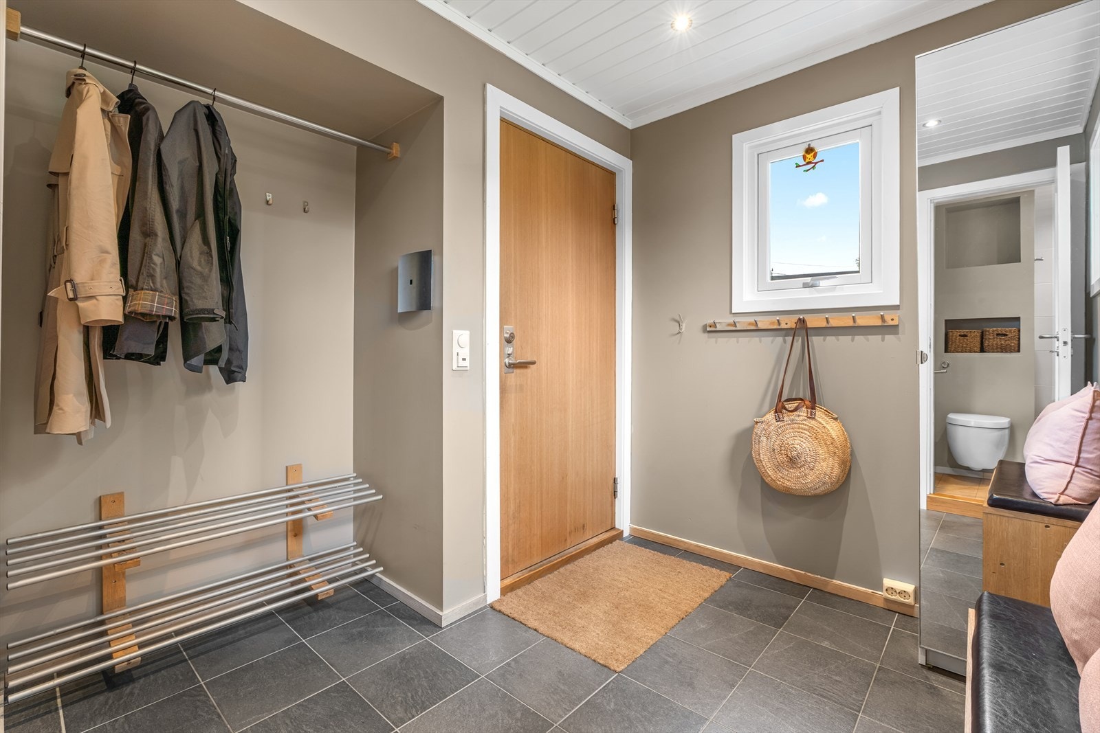 Her ønskes du velkommen inn i en flislagt entré med varmekabler. Rommet har god plass til å henge fra seg ytterklær. Galleribilde