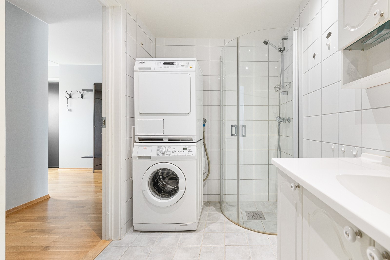 Badet er innredet med servant i baderomsinnredning, dusjhjørne, toalett og opplegg for plass for vaskemaskin og tørketrommel. Galleribilde