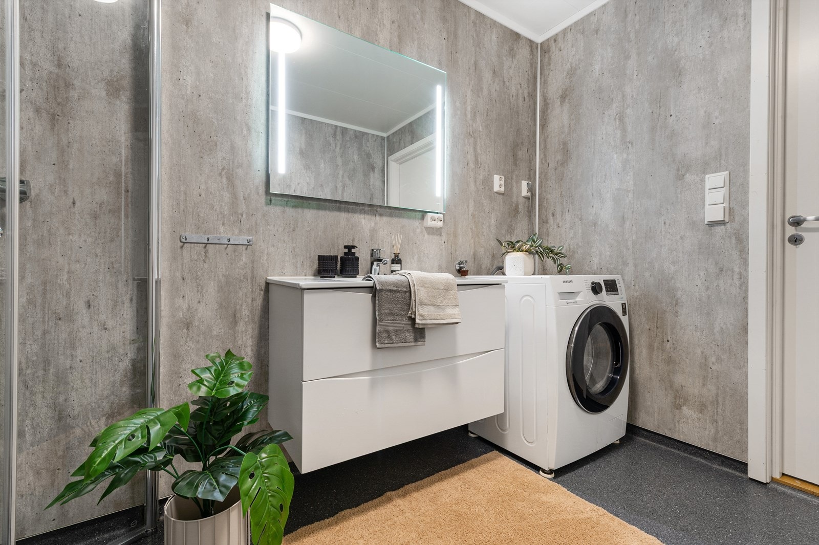 Badet har servant med underskap, speil med integrert belysning og opplegg for vaskemaskin. Galleribilde
