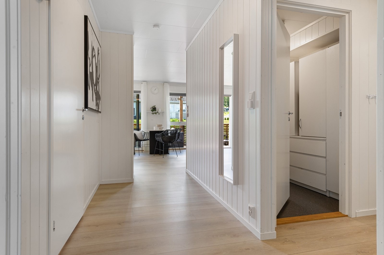Gjennomgående laminatgulv og lyse panelplater på veggene skaper en enhetlig stil. Galleribilde