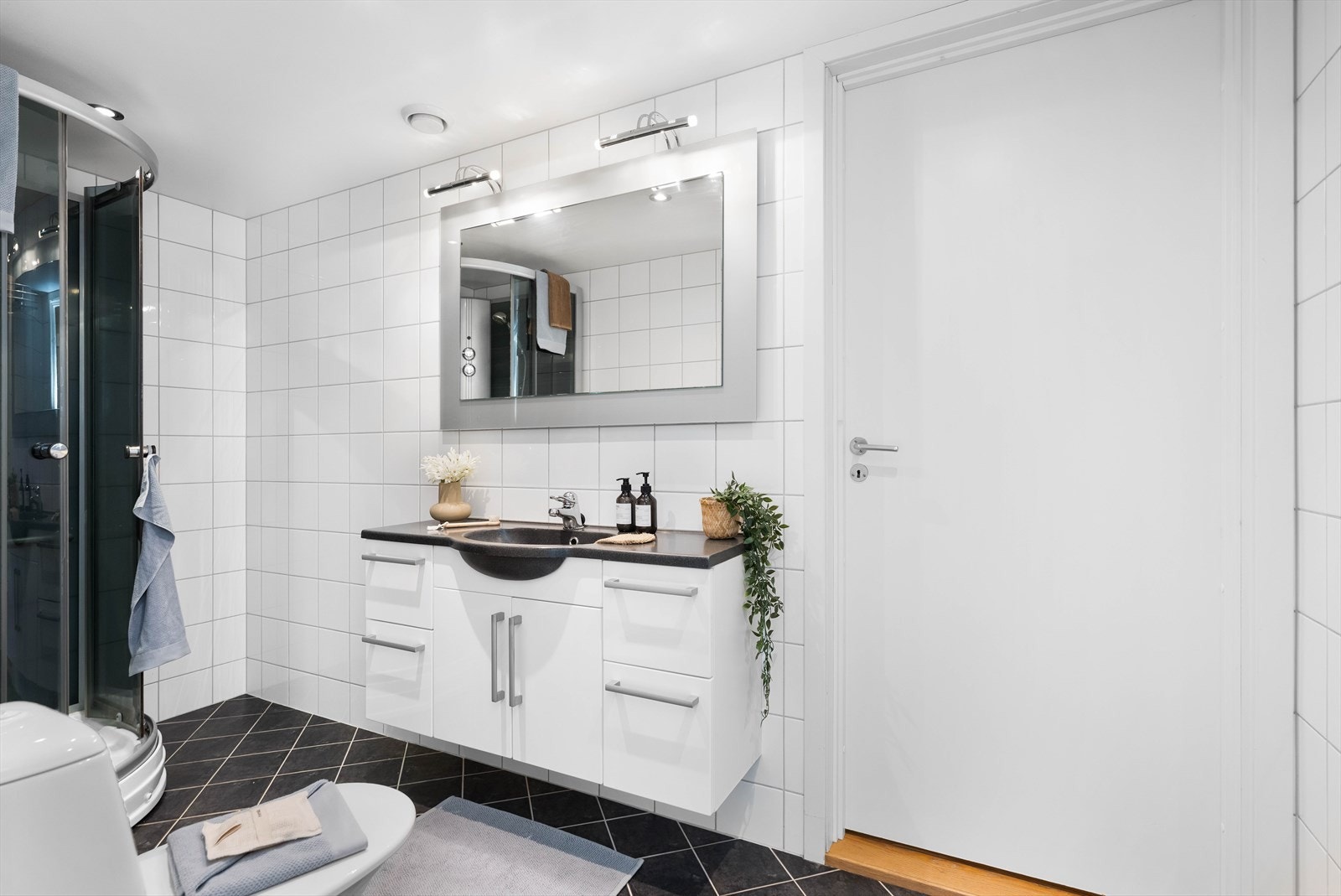 Badet har dusjkabinett og servantinnredning med skuffer og skap. Galleribilde