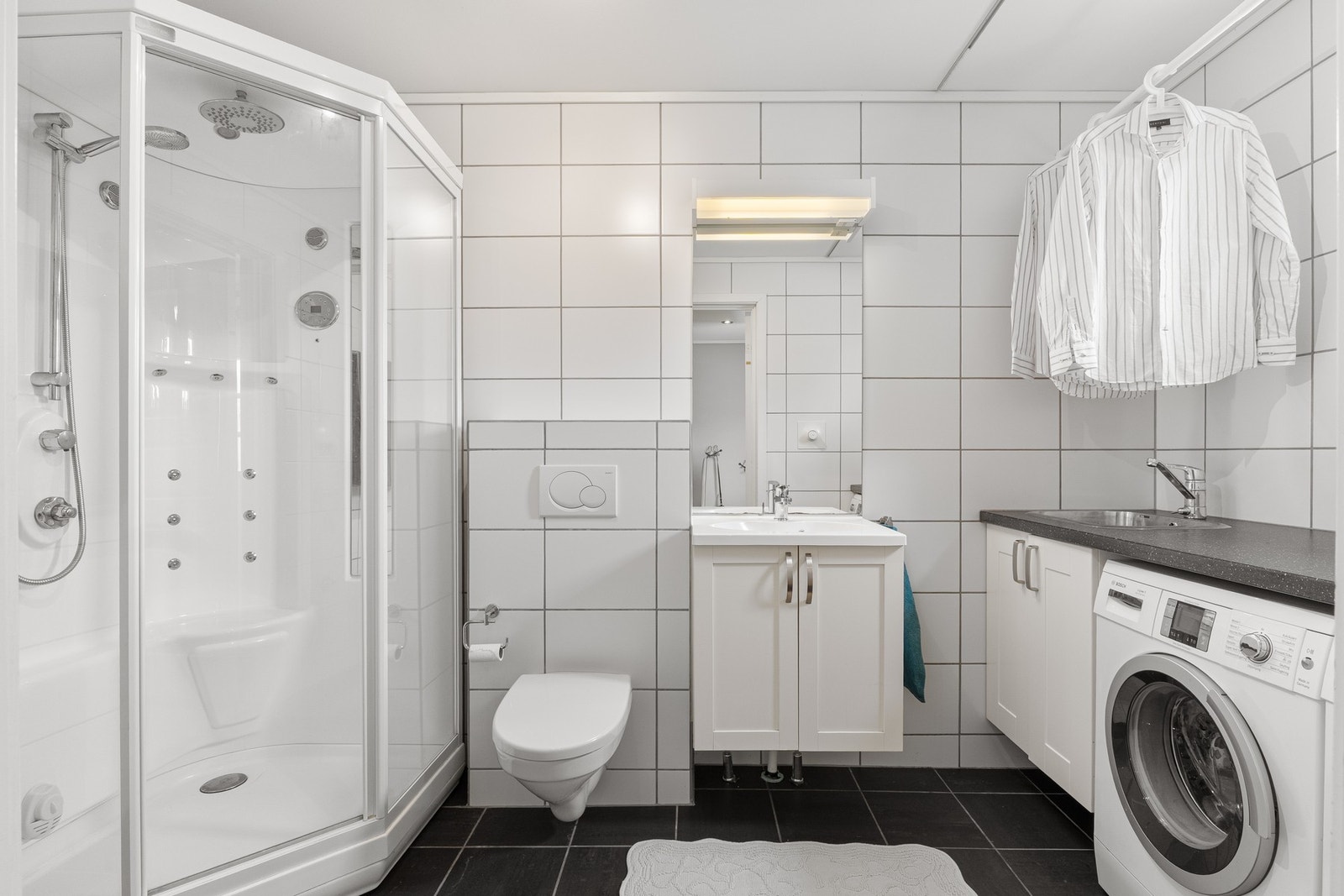 Badet er innredet med stor dusj, servant og vegghengt toalett. Galleribilde