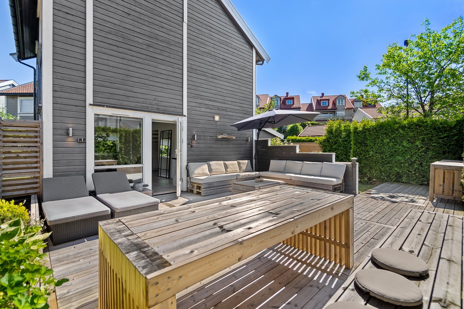 Den frodige hekken bidrar til privatliv og en lun atmosfære, mens den romslige treterrassen gir flotte muligheter for avslapning og hyggelige sommerdager i solen. Galleribilde