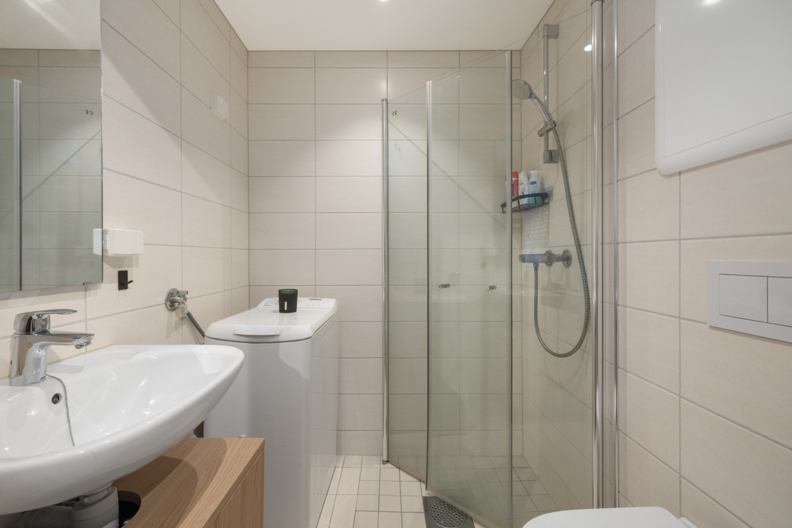 Badet har et tidløst uttrykk med flislagte overflater, dusjhjørne og en praktisk planløsning. Galleribilde