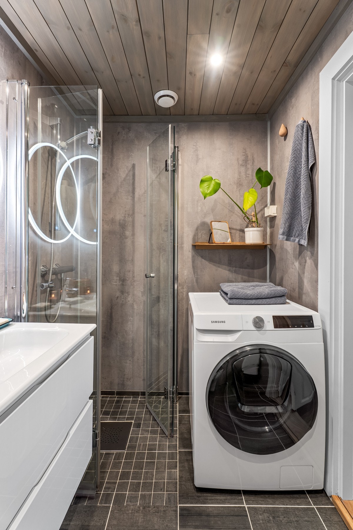Badet har flislagt gulv med varmekabler, romslig dusj og opplegg for vaskemaskin. Galleribilde