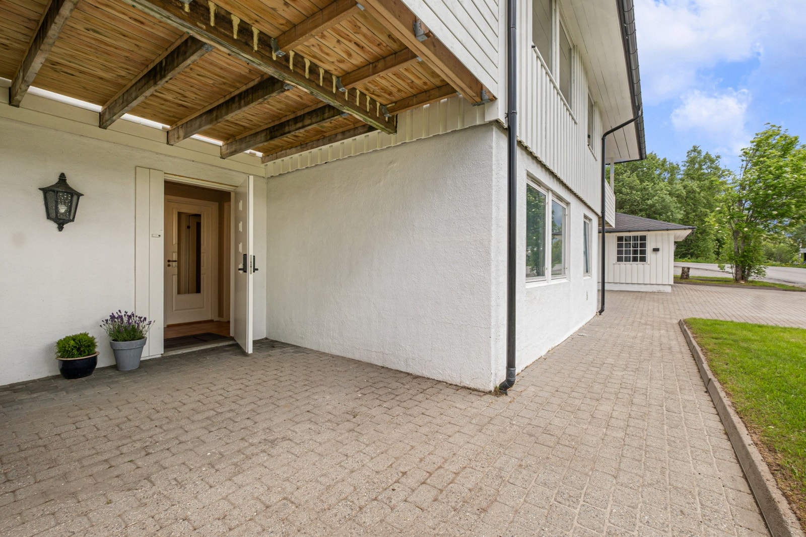 Overbygget inngangsparti med belegningsstein på bakken. Galleribilde