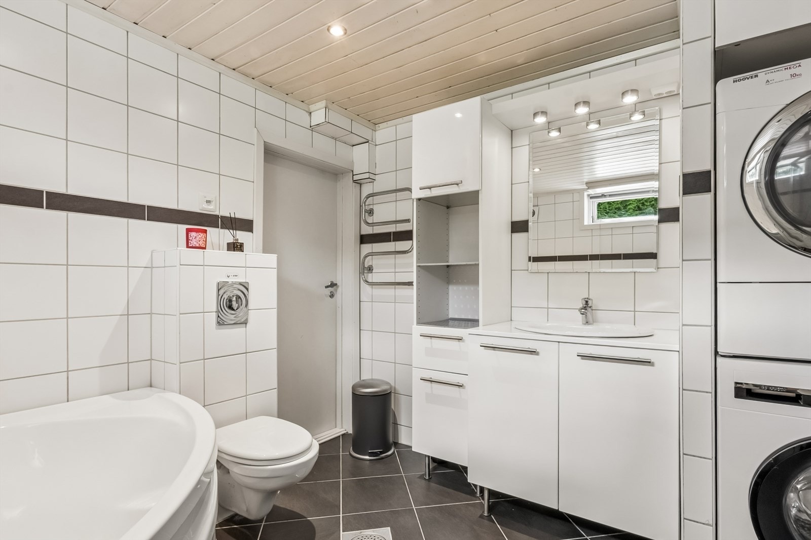 Badet i kjelleren har flislagt gulv med varmekabler og opplegg for vaskemaskin. Galleribilde