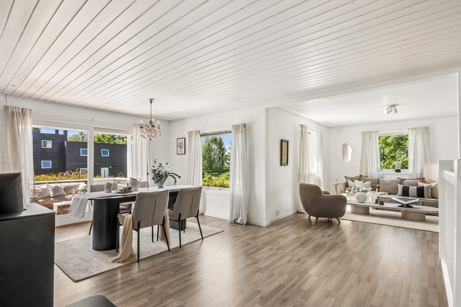 Stuen har en åpen løsning mot spisestue og kjøkken, med laminatgulv og malt trepanel i himling. Galleribilde