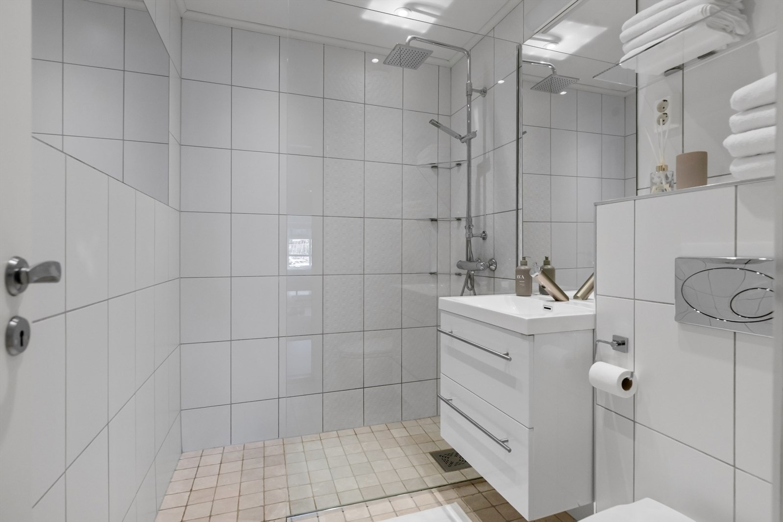 Heldekkende servant med praktiske underskuffer gir gode oppbevaringsmuligheter, mens speil, belysning og innfelte speilflater i flis. Galleribilde