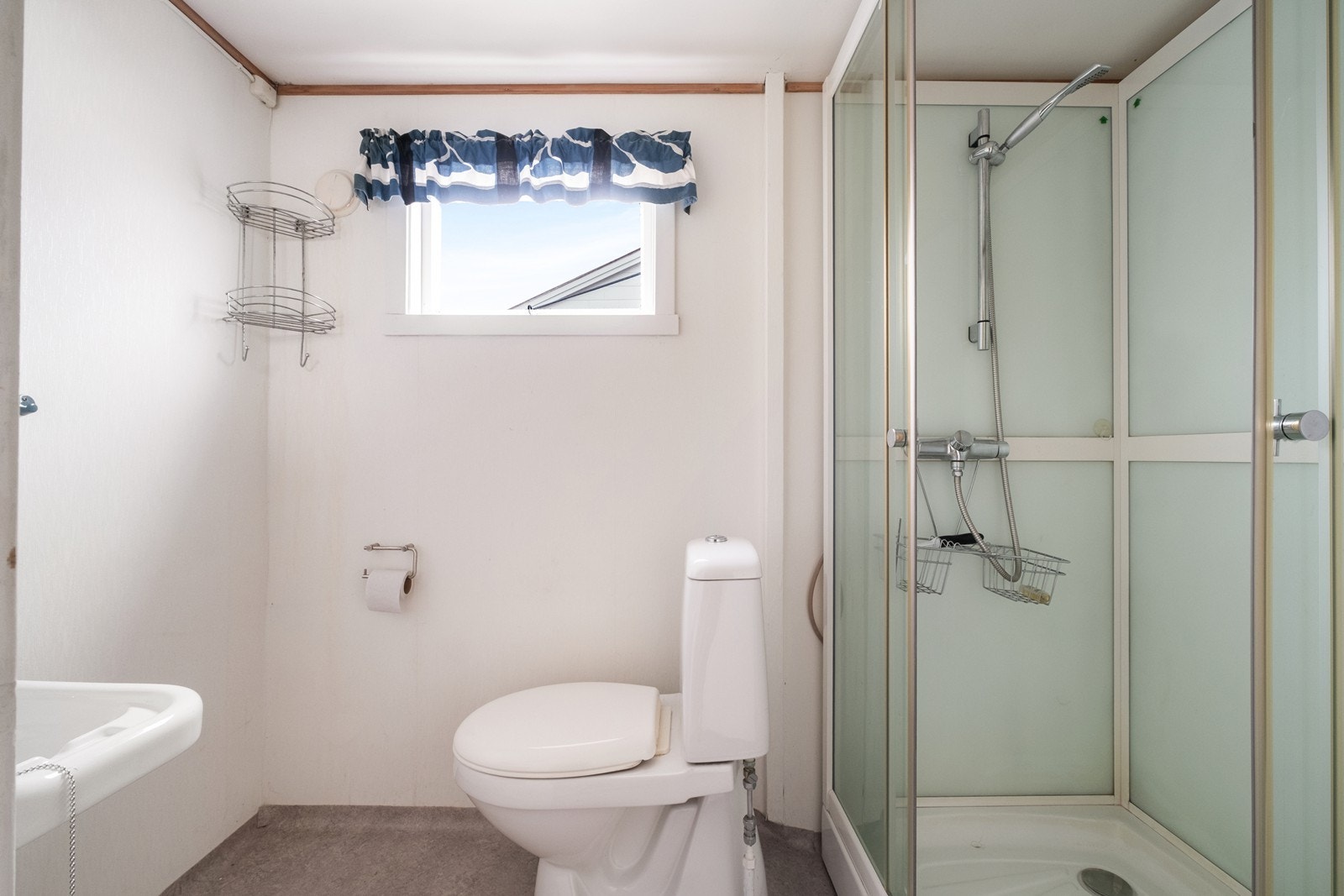 Badet er utstyrt med toalett, dusjkabinett og en enkel servant. Galleribilde