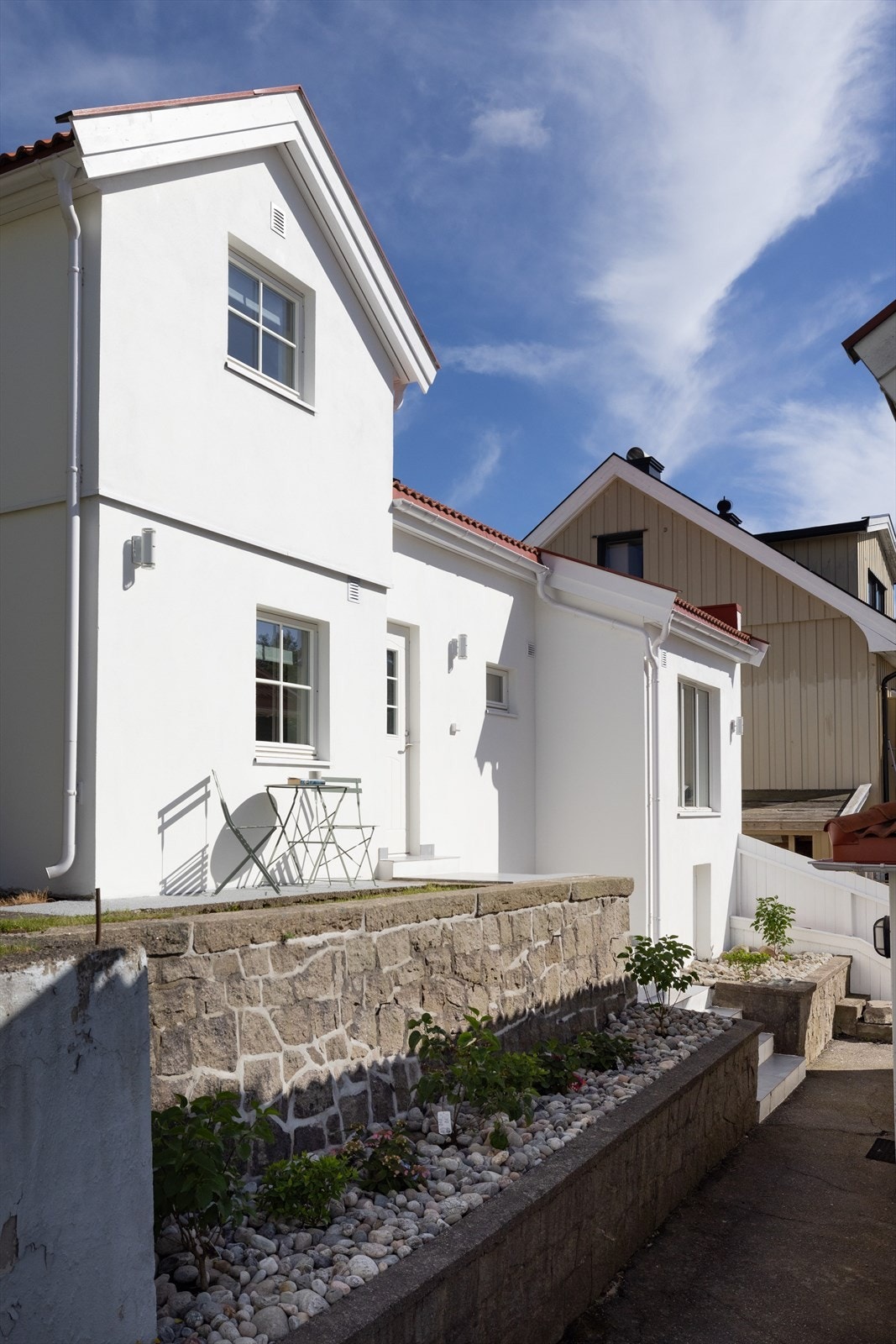 Granittstøttemur med beplantning og elvestein rammer inn fasaden på en sjarmerende måte. Galleribilde